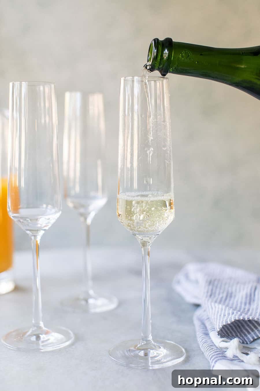 Sparkling white wine being poured into a Champagne Flute, illustrating the first step of making a mimosa.