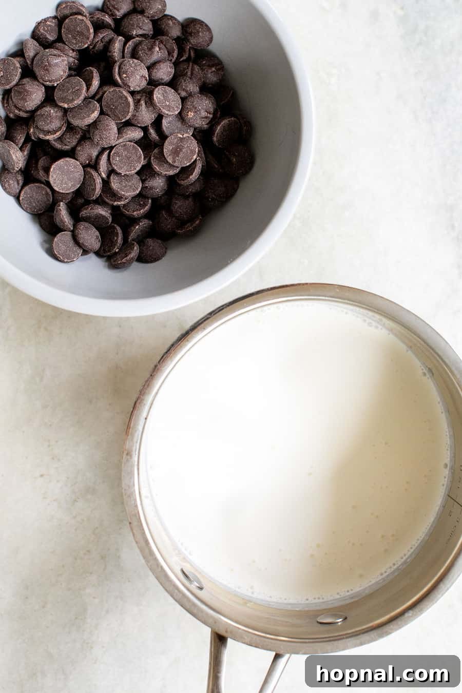 Close-up shot of heavy cream and shiny semisweet chocolate morsels, the two essential ingredients for ganache.