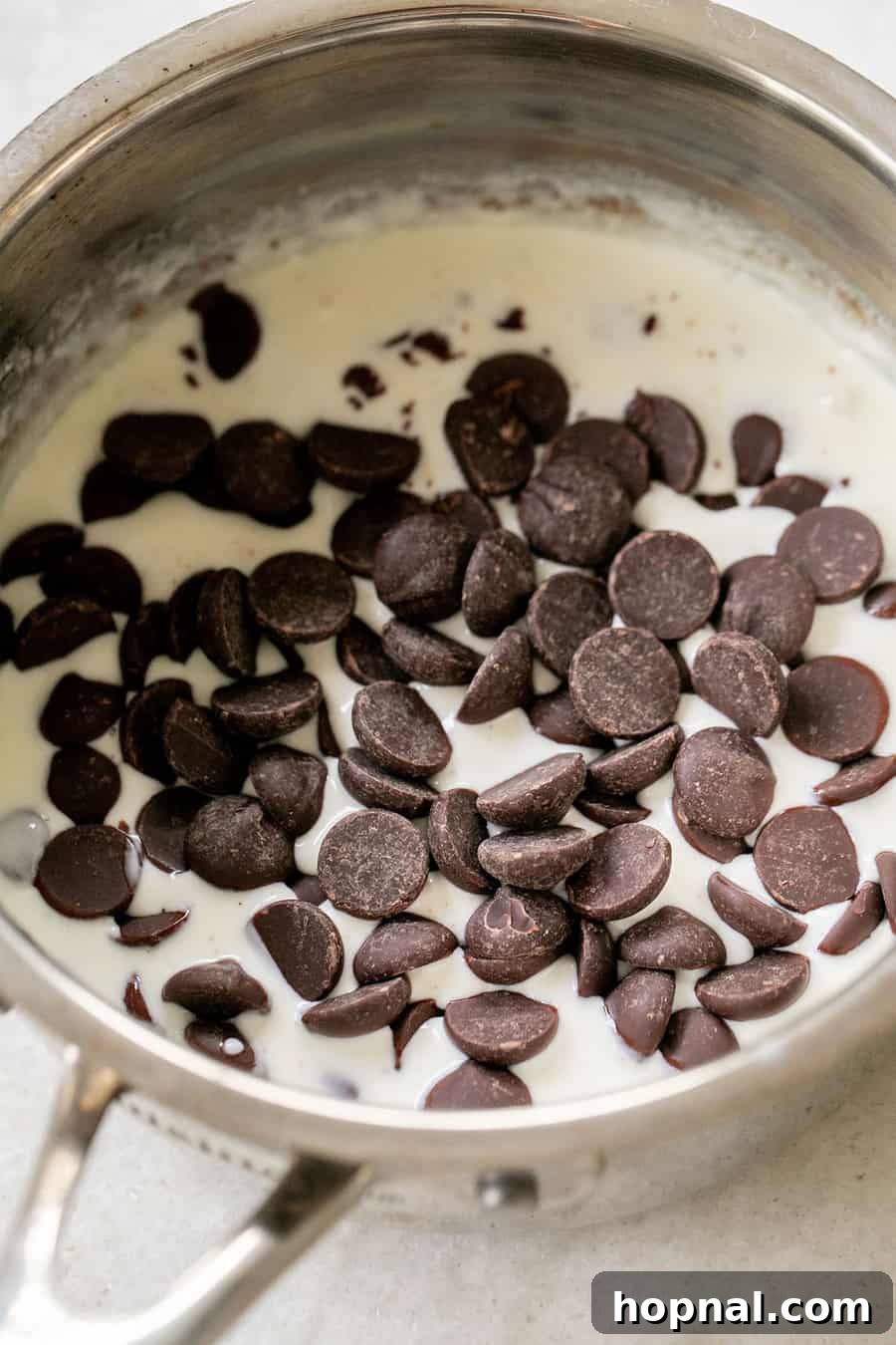 Semisweet chocolate morsels submerged in hot heavy cream, ready to be whisked into ganache.
