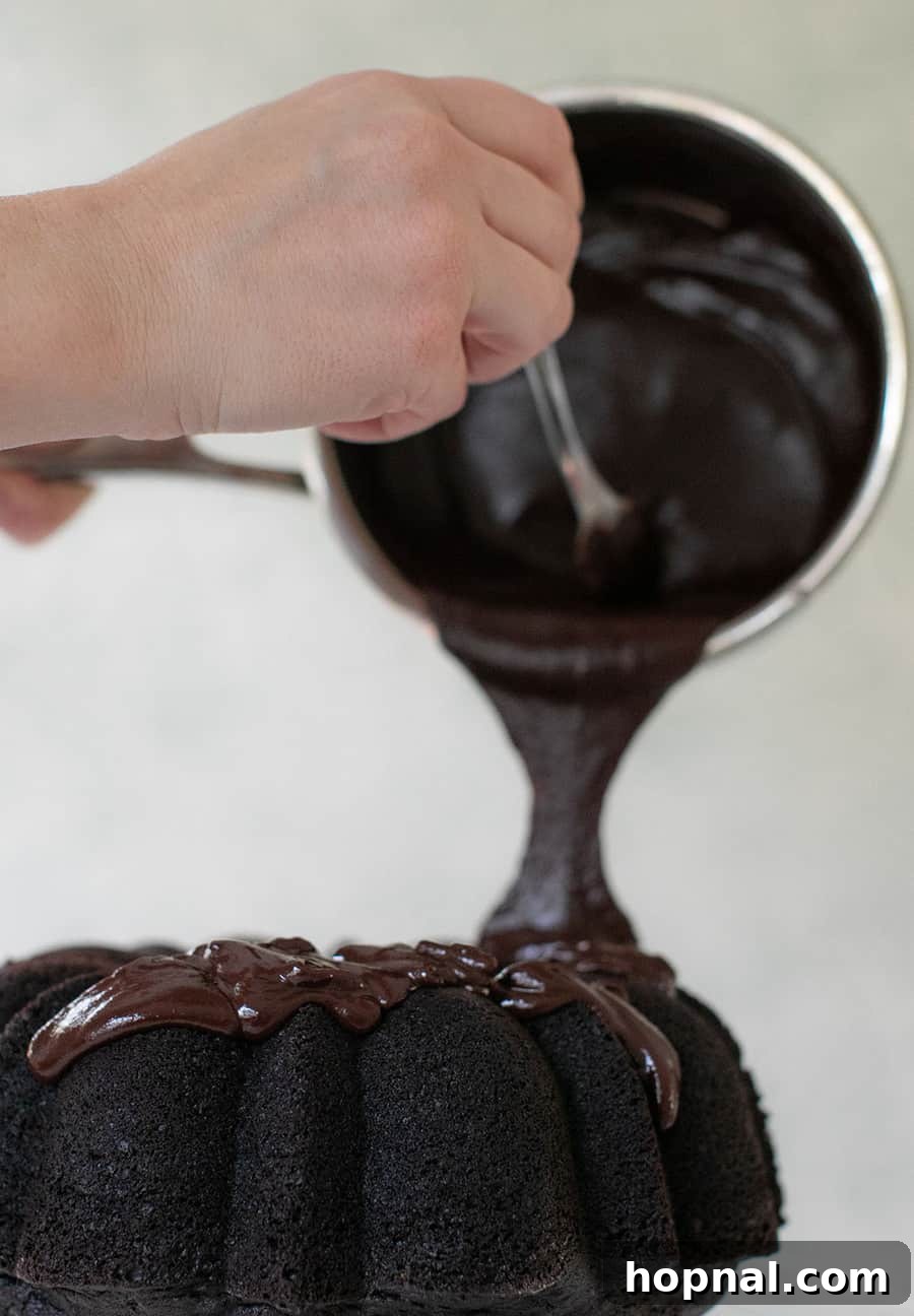 Thick, glossy chocolate ganache being poured generously over a beautifully baked bundt cake, creating an elegant glaze.