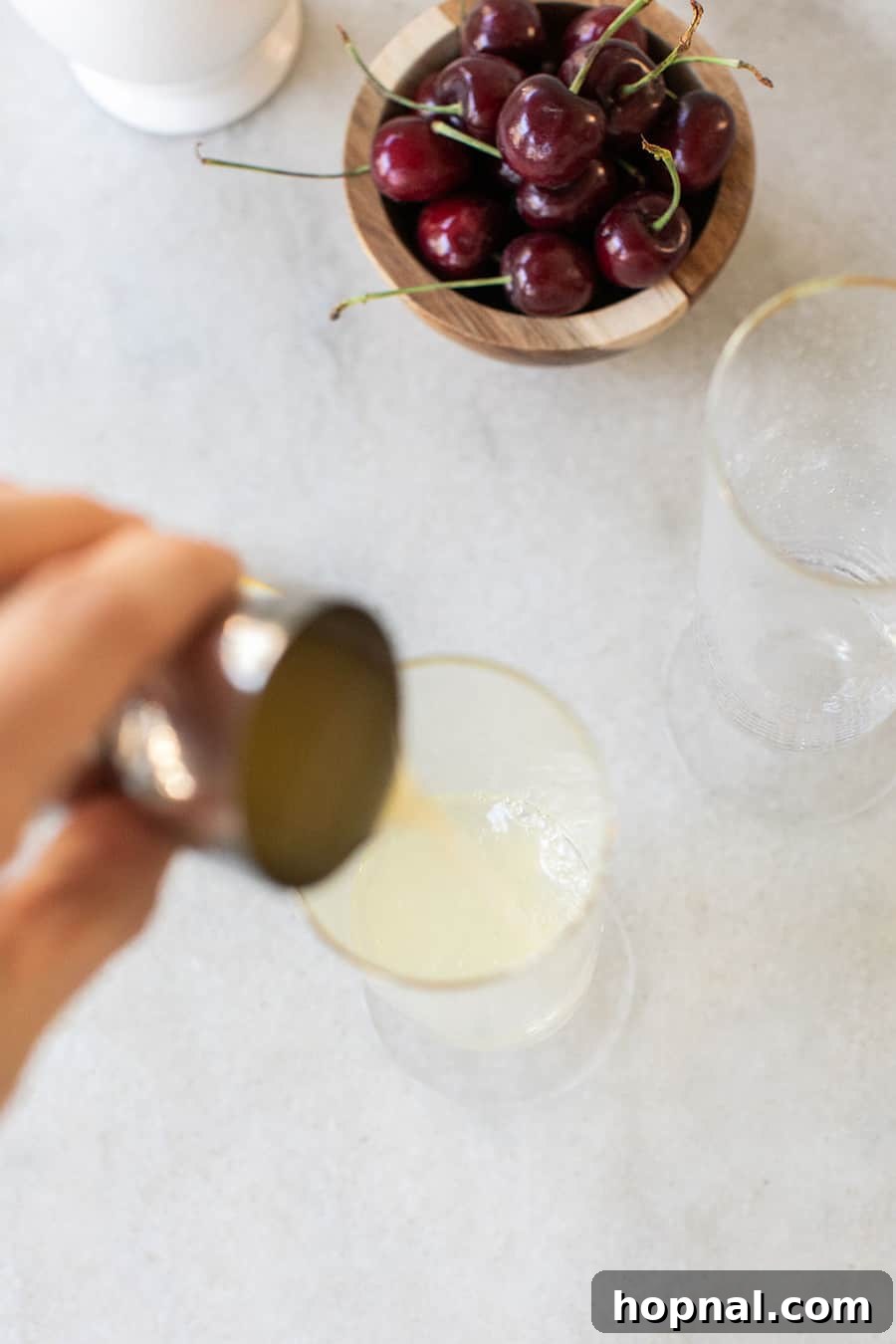 Pouring lemon juice into a Tom Collins glass