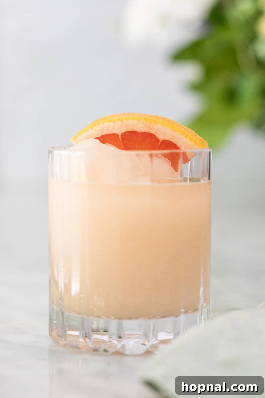 Frozen Paloma cocktail with grapefruit slices and a vibrant pink hue in a tall glass, perfect for summer.