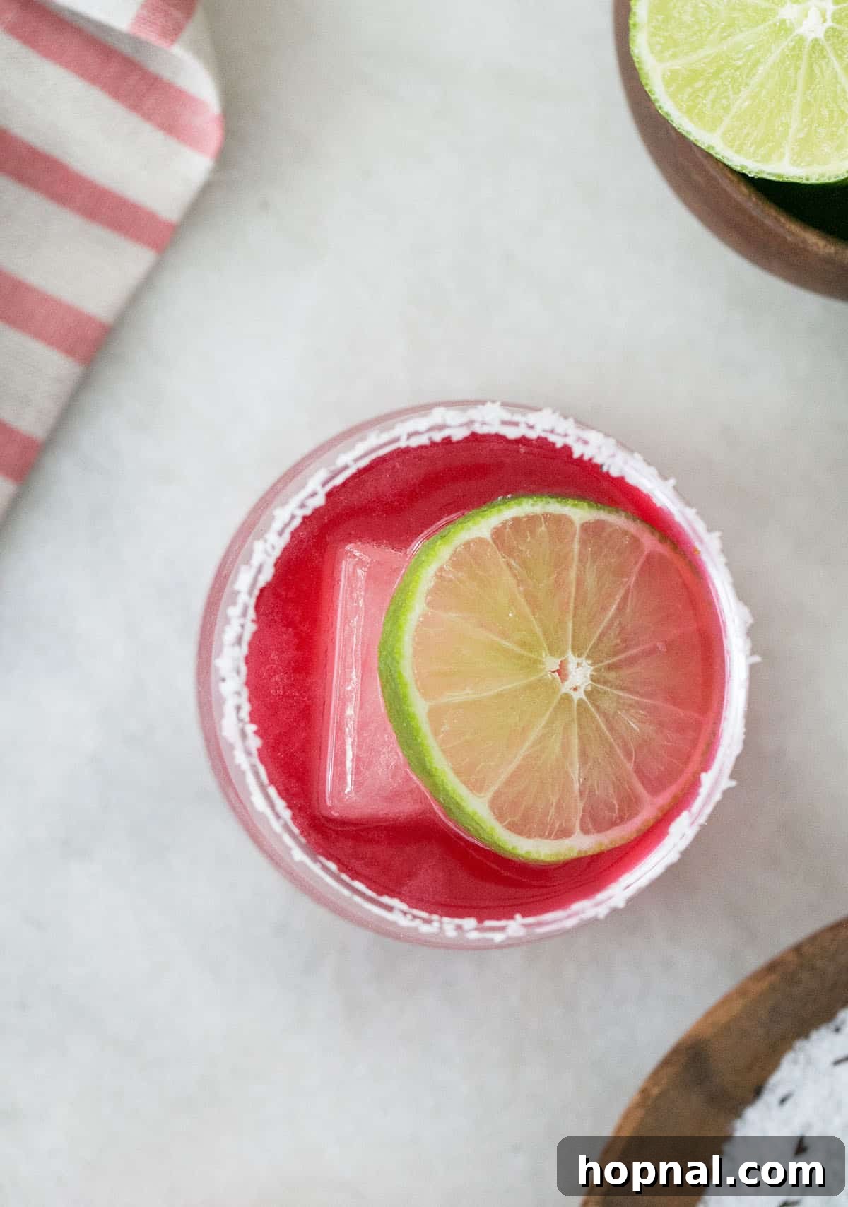 Vibrant pink Hibiscus Margarita in a glass with a lime garnish, a beautiful tequila twist.