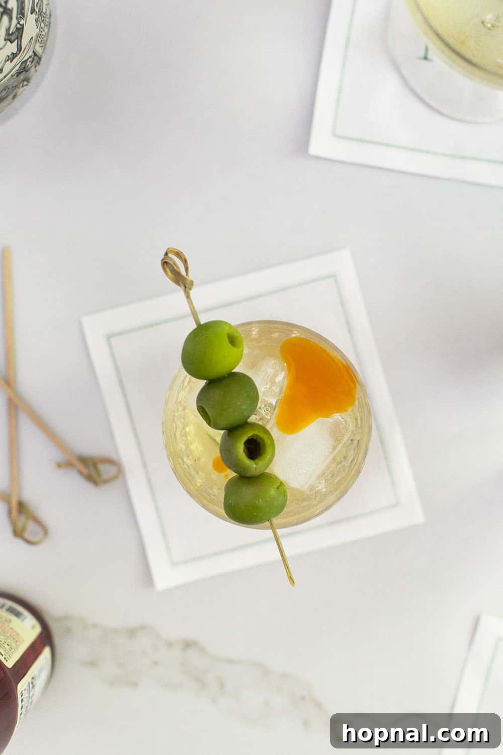 Dirty Martini made with tequila, garnished with three green olives on a pick.
