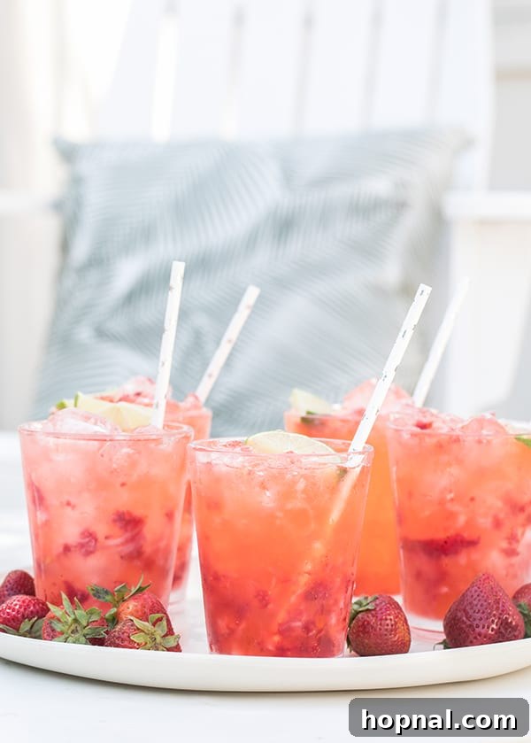 Strawberry Tequila Sodas served in glasses with muddled strawberries and fresh lime wedges.