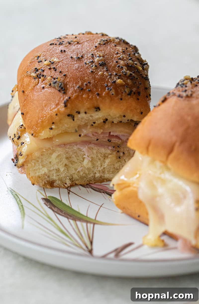 Your Ultimate Easter Recipe Collection 12 Delicious ham and cheese sliders on sweet Hawaiian rolls, topped with savory sauce.
