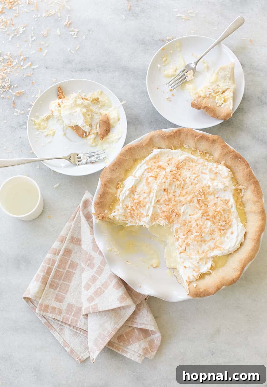 A decadent slice of coconut cream pie, topped generously with fluffy whipped cream and golden toasted shredded coconut.