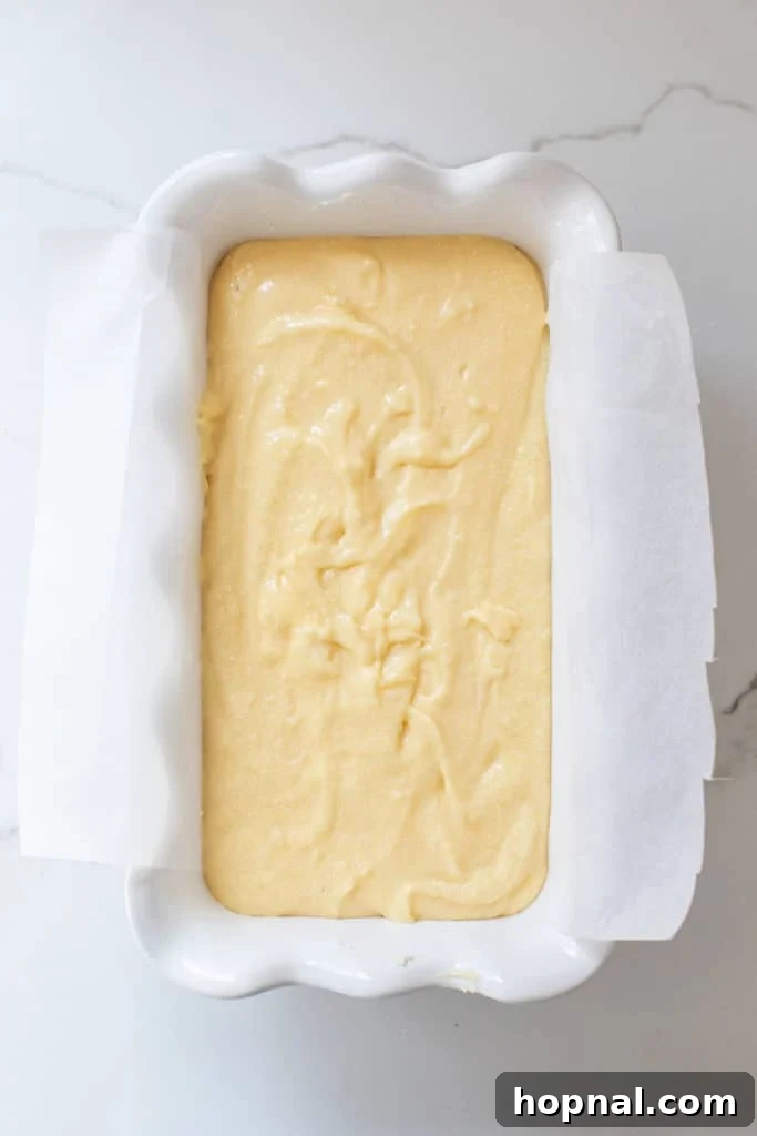 Timeless Pound Cake Perfection 7 Pound cake batter expertly poured into a parchment-lined loaf pan, ready for baking, highlighting the preparation for easy removal.