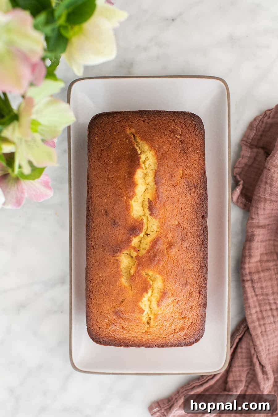 Timeless Pound Cake Perfection 8 A perfectly baked old-fashioned pound cake loaf in a ceramic ruffled pan, featuring a beautiful golden crust and a slight crack on top, indicating its readiness.