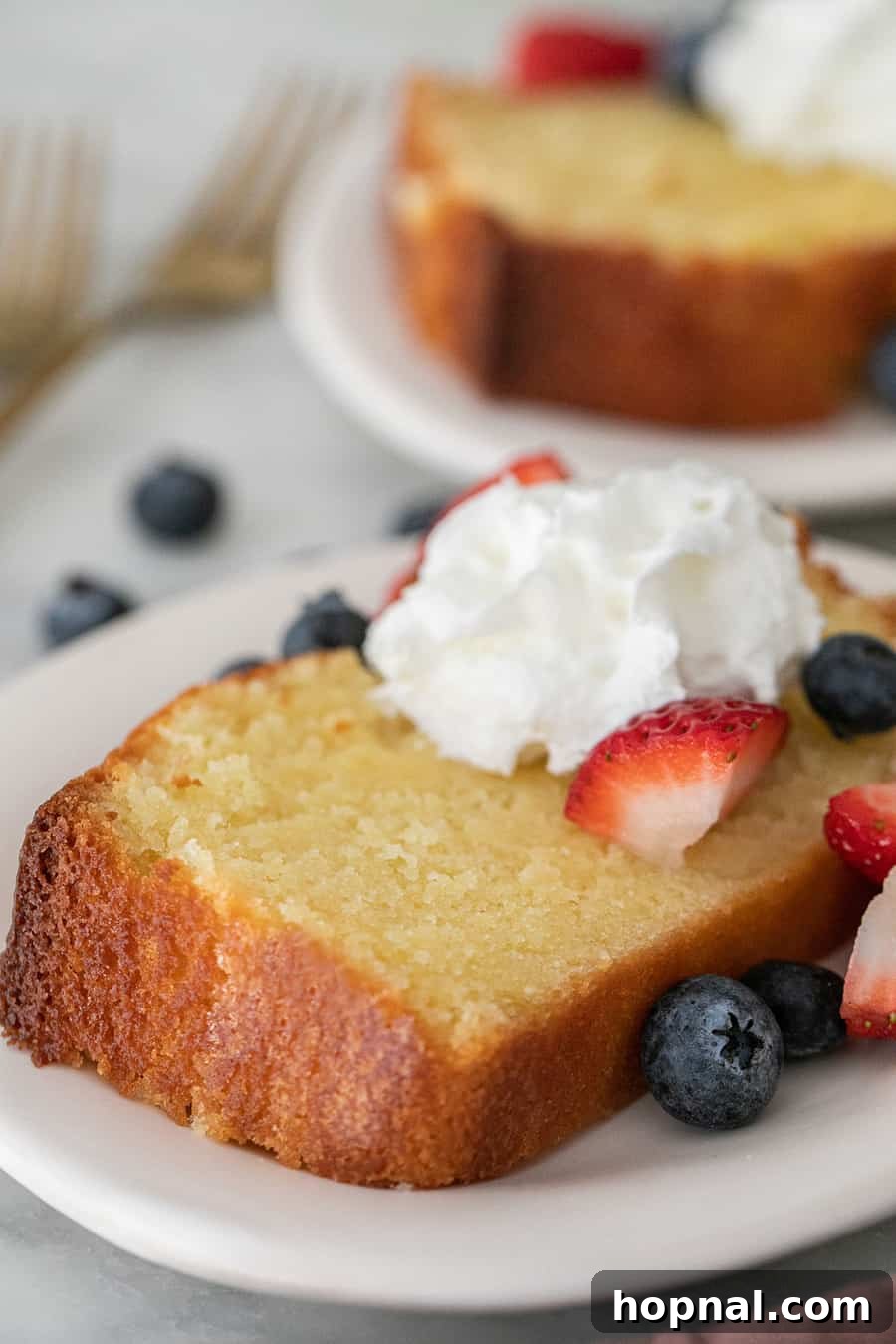Timeless Pound Cake Perfection 10 A moist old-fashioned pound cake loaf, sliced and garnished with fresh whipped cream and an assortment of colorful berries, ready to be served.
