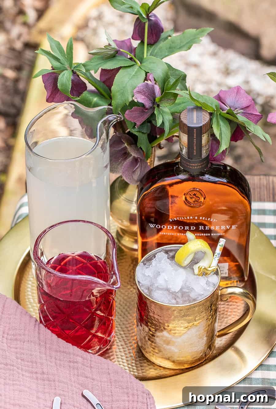Cranberry juice, lemonade, and Woodford Reserve neatly arranged on a gold tray, ready for cocktail mixing.