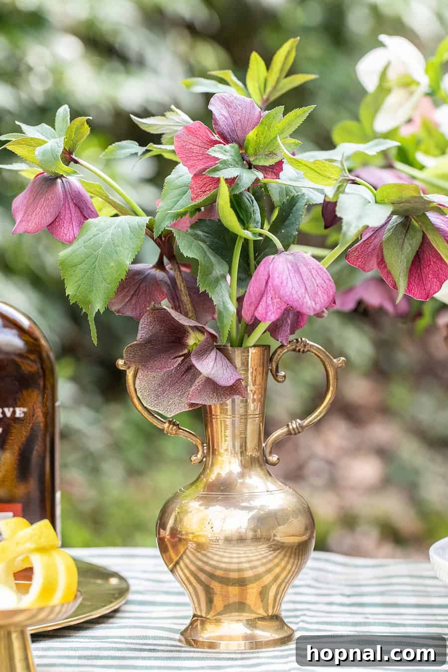 Flowers in an antique gold vase, resembling a trophy, for a sophisticated Kentucky Derby party setting.