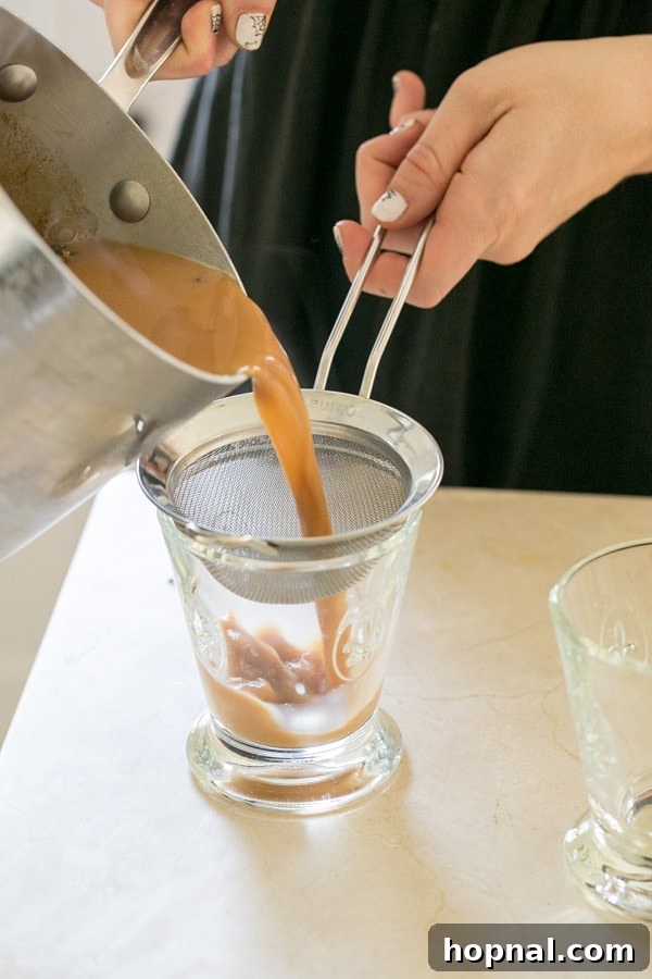 shot of pouring homemade chai tea through a sieve 