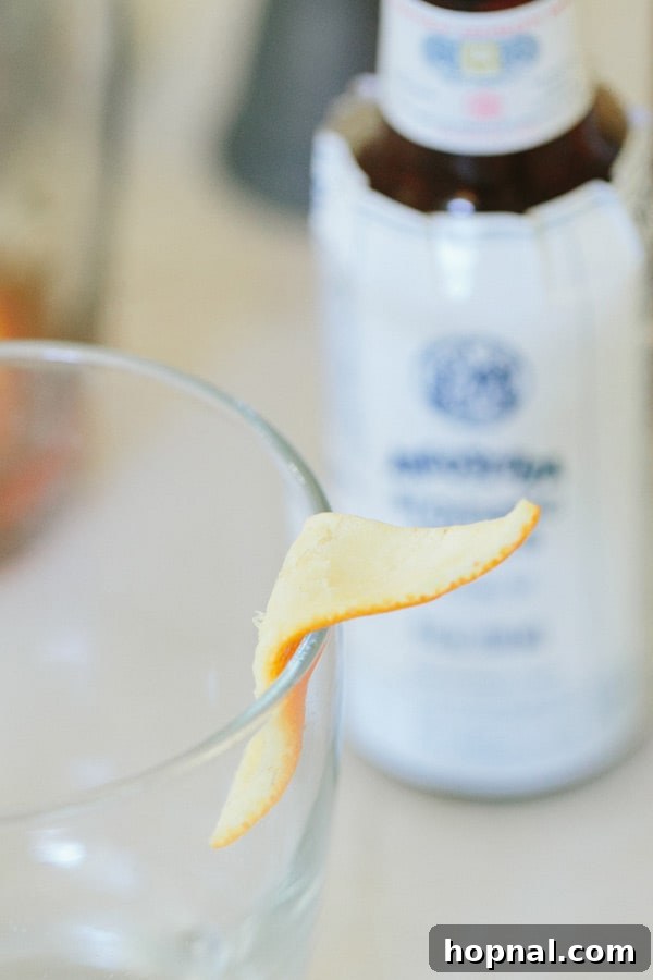 Close-up of a burnt orange peel on the edge of an Old Fashioned cocktail glass