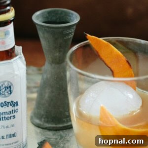 A perfectly crafted Burnt Orange Old Fashioned cocktail in a glass with ice and burnt orange peel