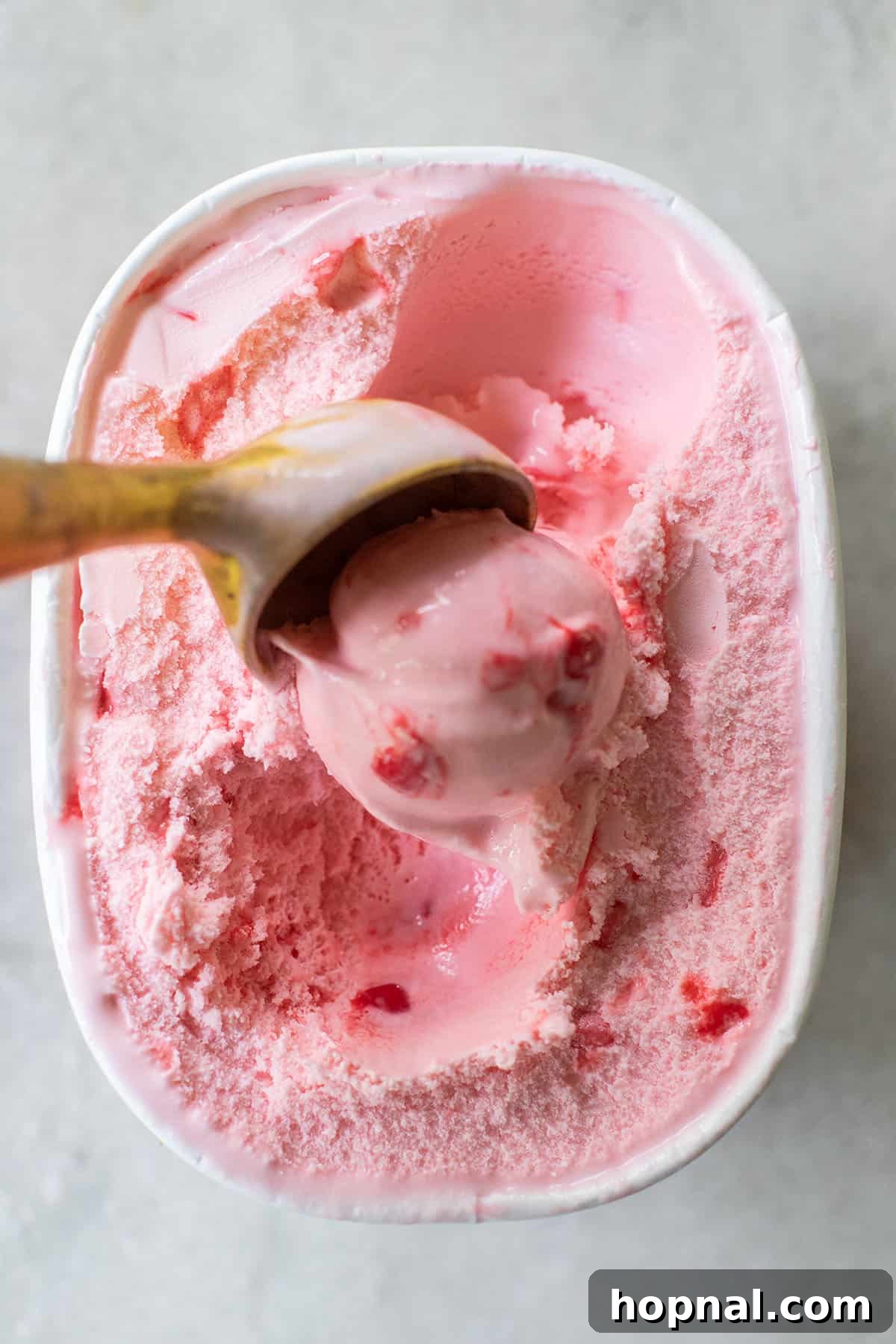Frosted Peppermint Punch 4 Pink peppermint ice cream being scooped out of a container into a punch bowl.