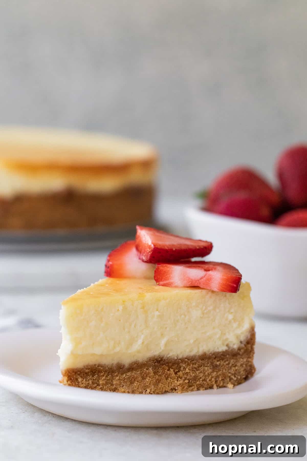 Irresistible Homemade Cheesecake 2 A perfectly sliced piece of creamy homemade cheesecake, elegantly topped with fresh strawberries, ready to be enjoyed.