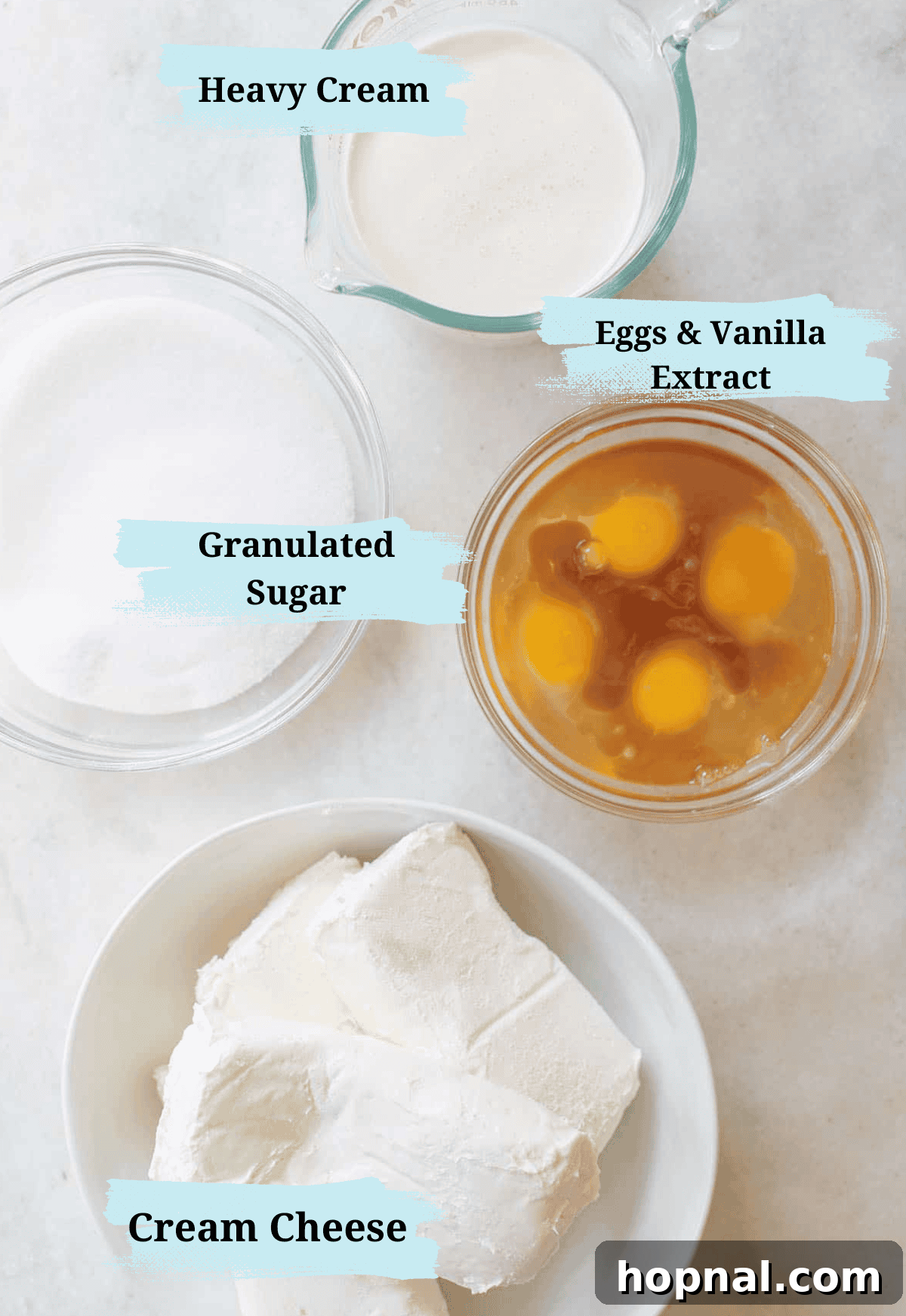 Irresistible Homemade Cheesecake 3 A collection of essential ingredients laid out for making a homemade cheesecake, including heavy cream, sugar, eggs, and cream cheese in separate bowls.