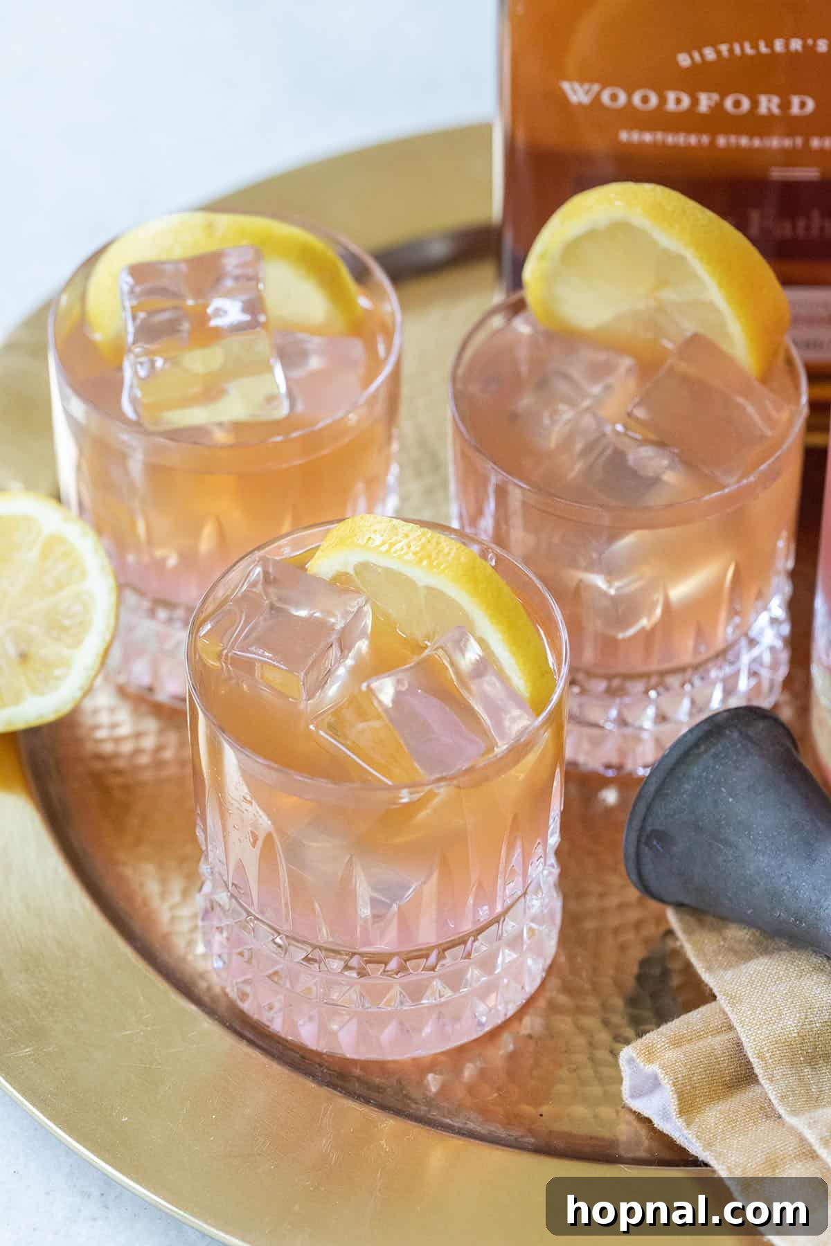 A refreshing whiskey lemonade cocktail in a short glass with ice and a lemon slice.
