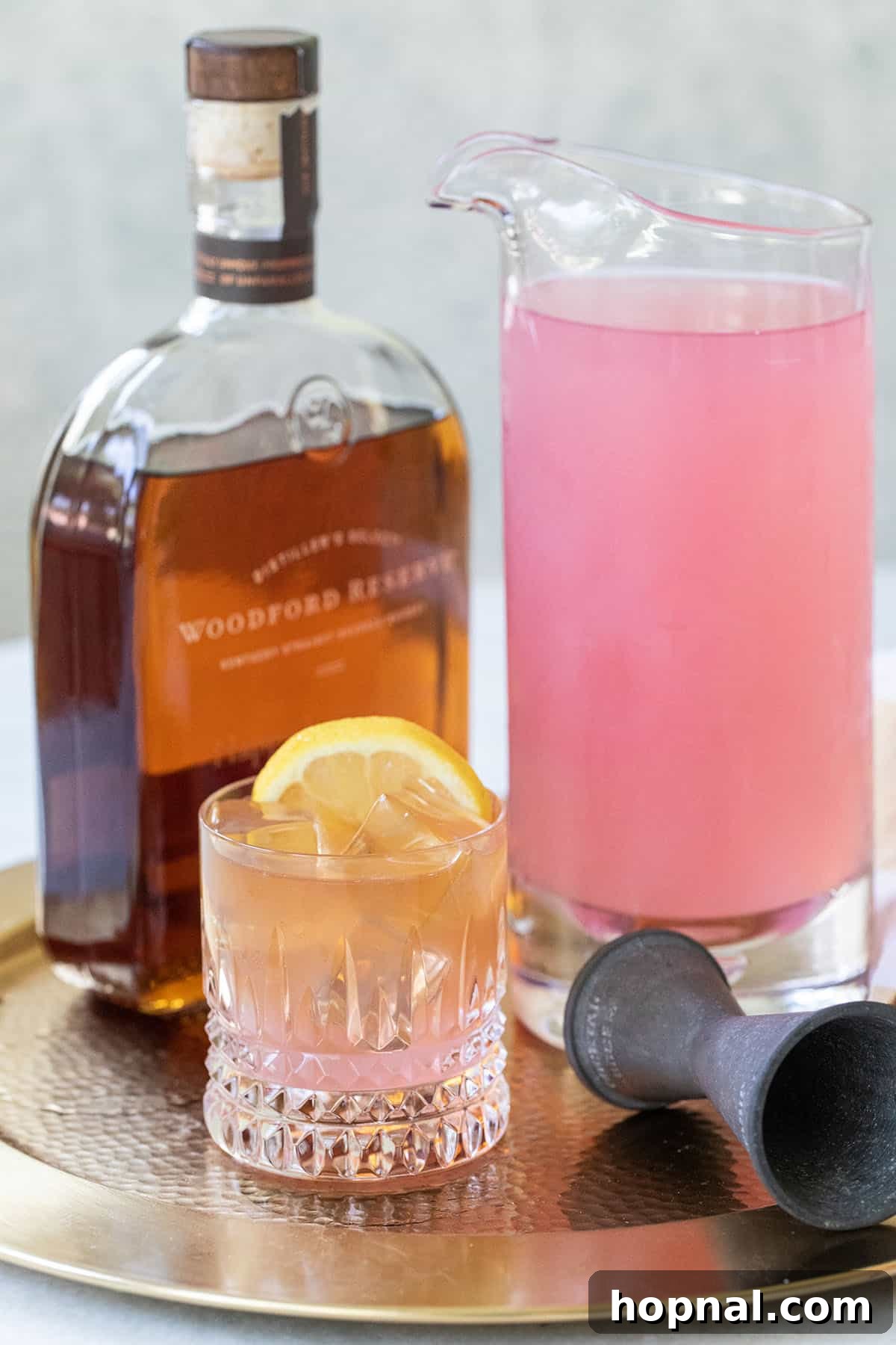 Ingredients for bourbon and pink lemonade cocktail displayed on a wooden surface.