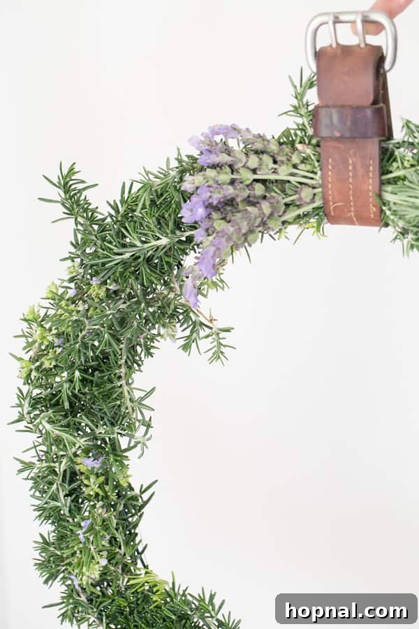 Close-up detailed shot of a finished fresh rosemary wreath, highlighting its lush texture, vibrant green leaves, and the subtle beauty of its natural elements. The amazing scent is almost palpable.