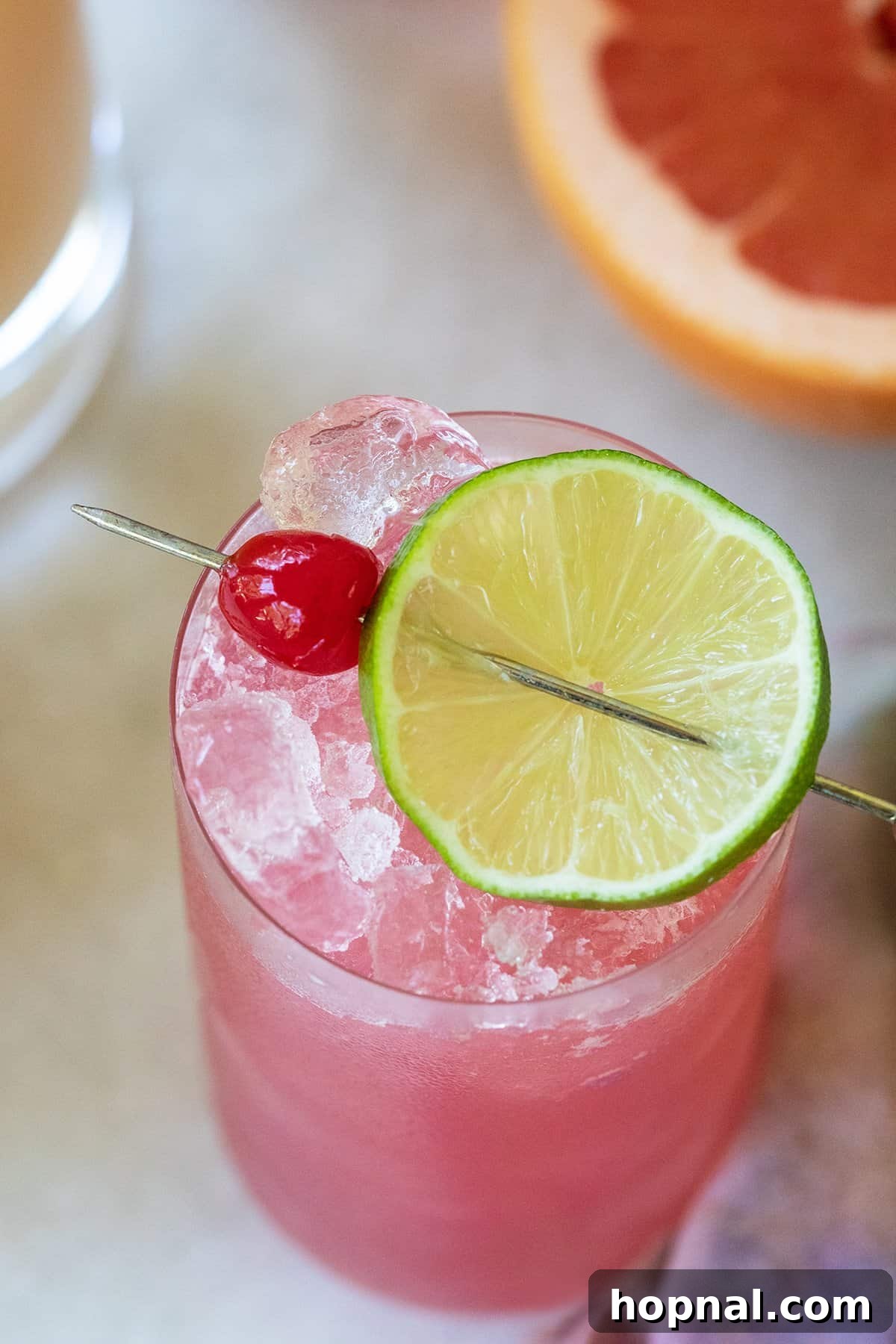 Pink Sea Breeze cocktail with lime and cherry garnish.