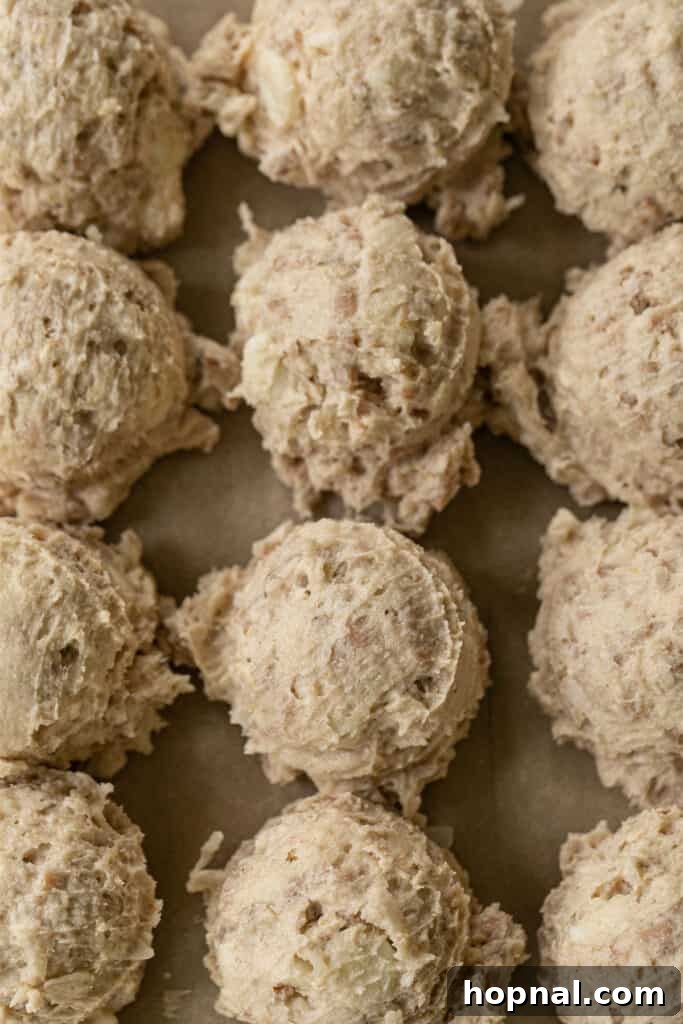 Ultimate Kitchen Sink Cookies 4 Portions of unbaked cookie dough scooped onto a baking sheet, ready for the oven.
