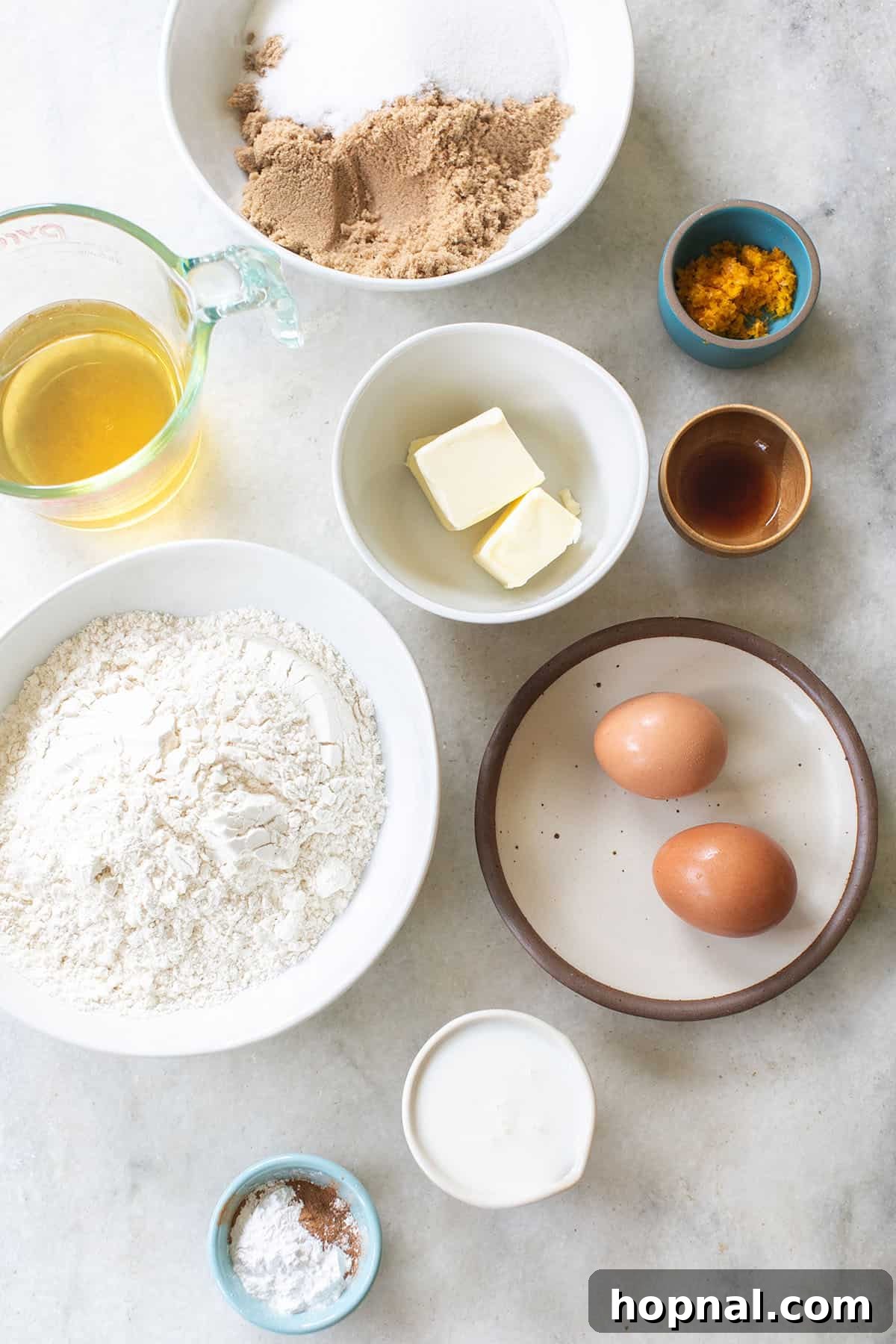 Bowls filled with essential baking ingredients such as flour, butter, eggs, buttermilk, and vanilla extract, arranged for making donuts.
