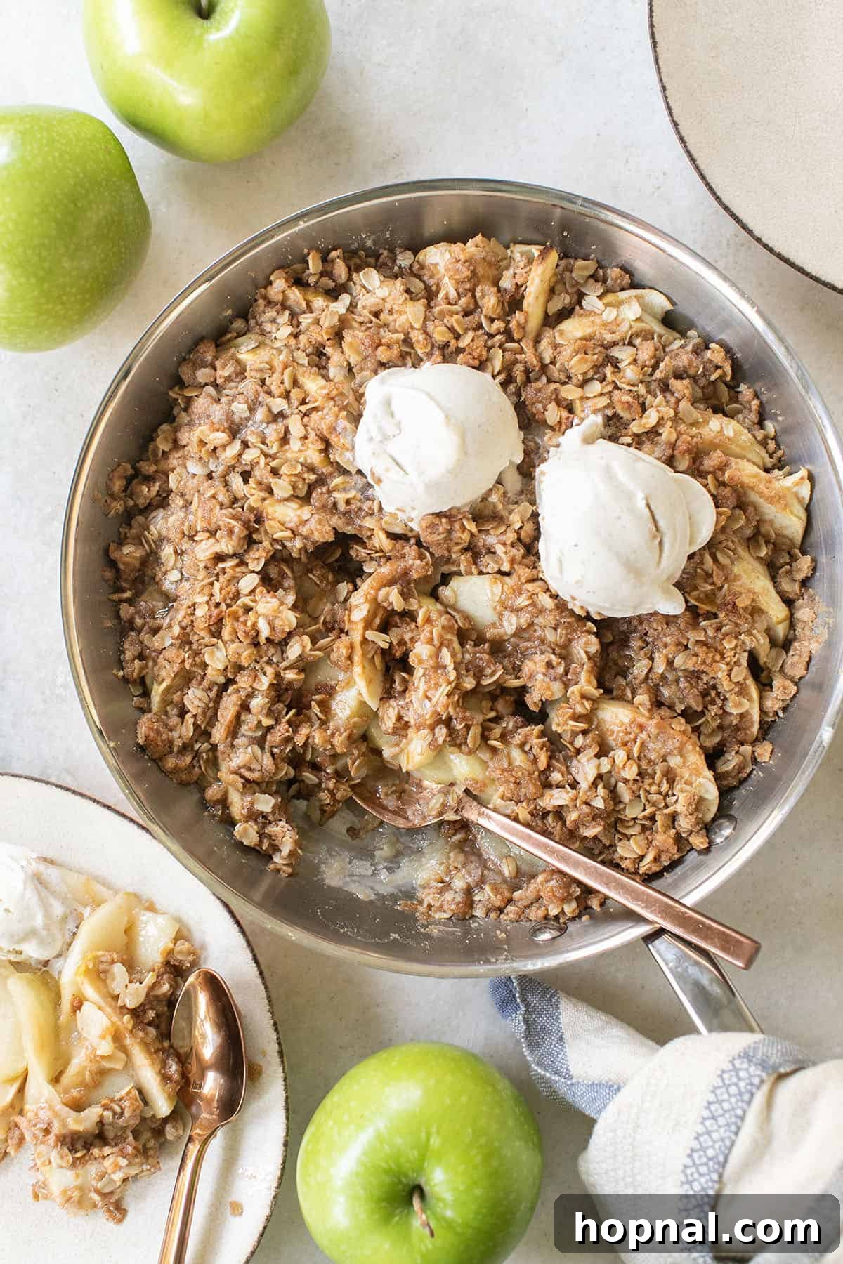 Warm homemade apple crisp served with a generous scoop of creamy vanilla ice cream, ready to be enjoyed.