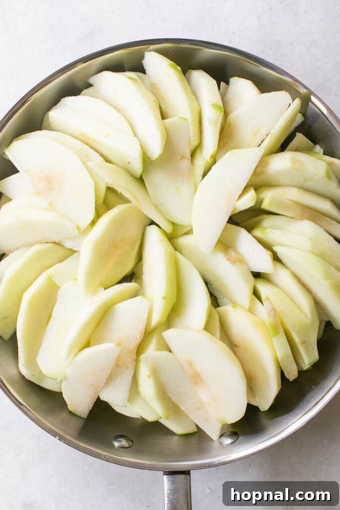 Thinly sliced apples evenly layered in a round baking dish, ready for the crisp topping.