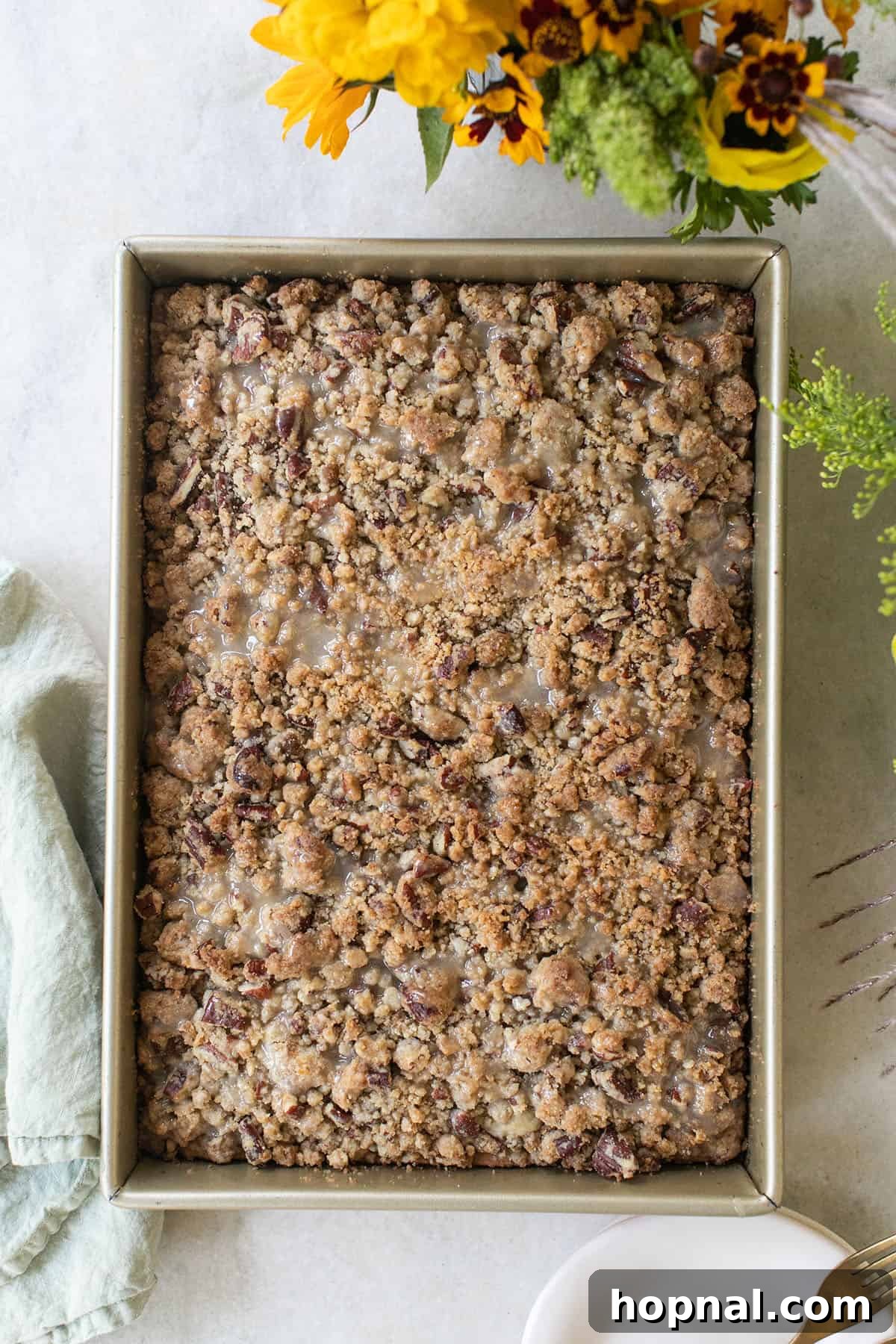 A golden crumb cake baking in a pan, topped with streusel, fresh from the oven.