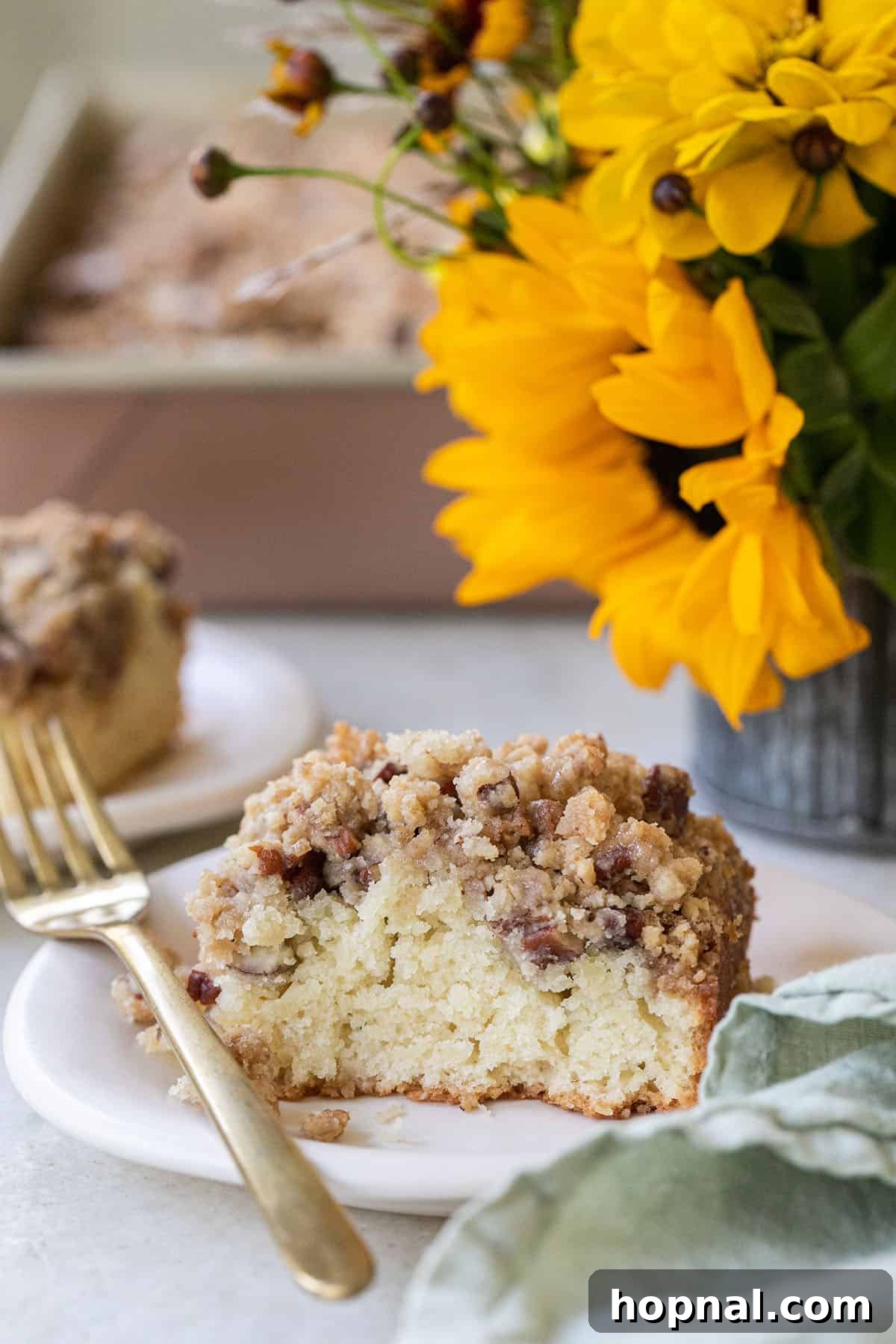 A perfectly sliced piece of crumb cake resting on a delicate plate with a gold spoon, ready to be enjoyed.