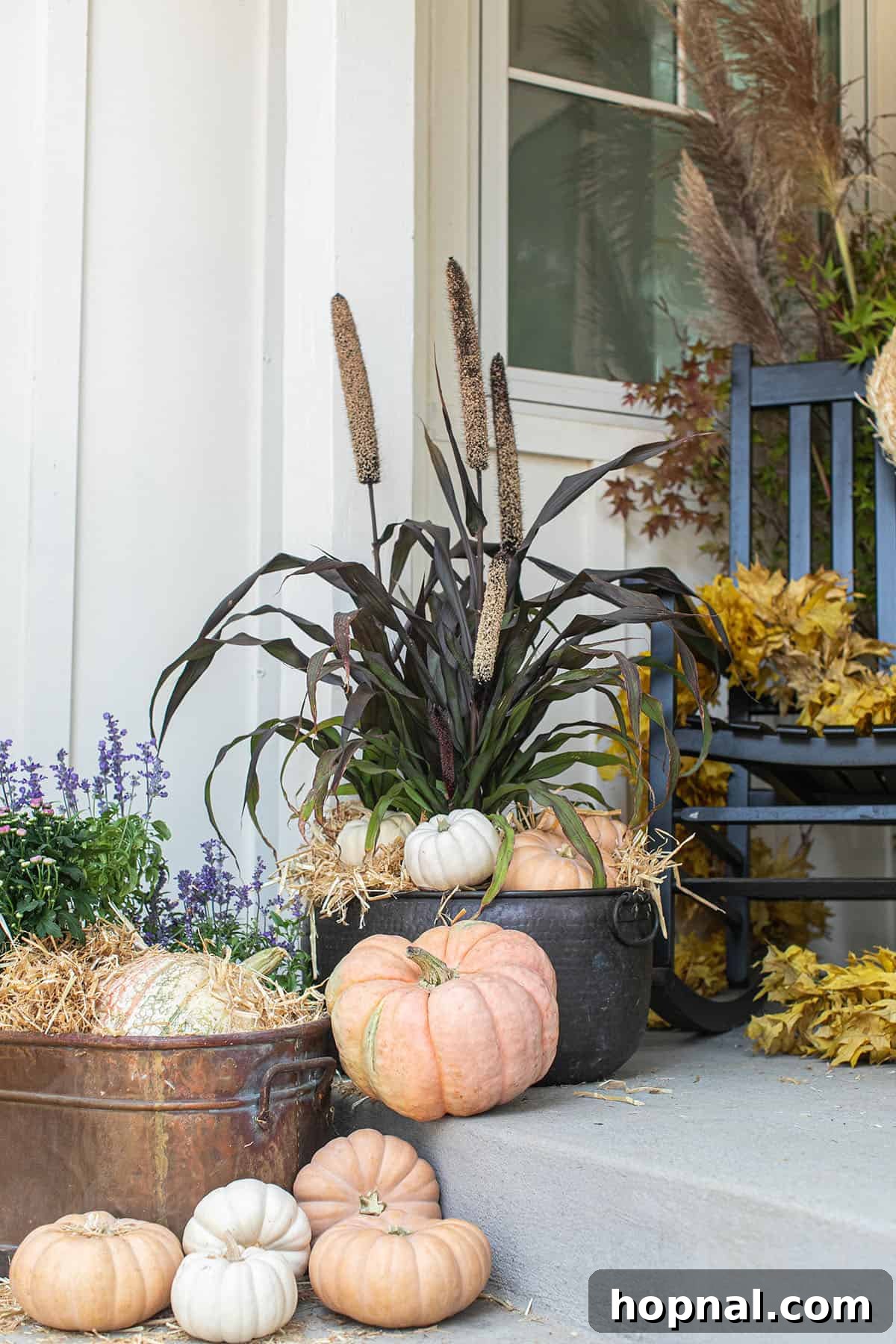 Fall porch decor with unique pumpkins and flowers in copper pots. A cozy front porch decorated for fall featuring a variety of unique pumpkins and colorful autumn flowers elegantly arranged in striking copper pots.