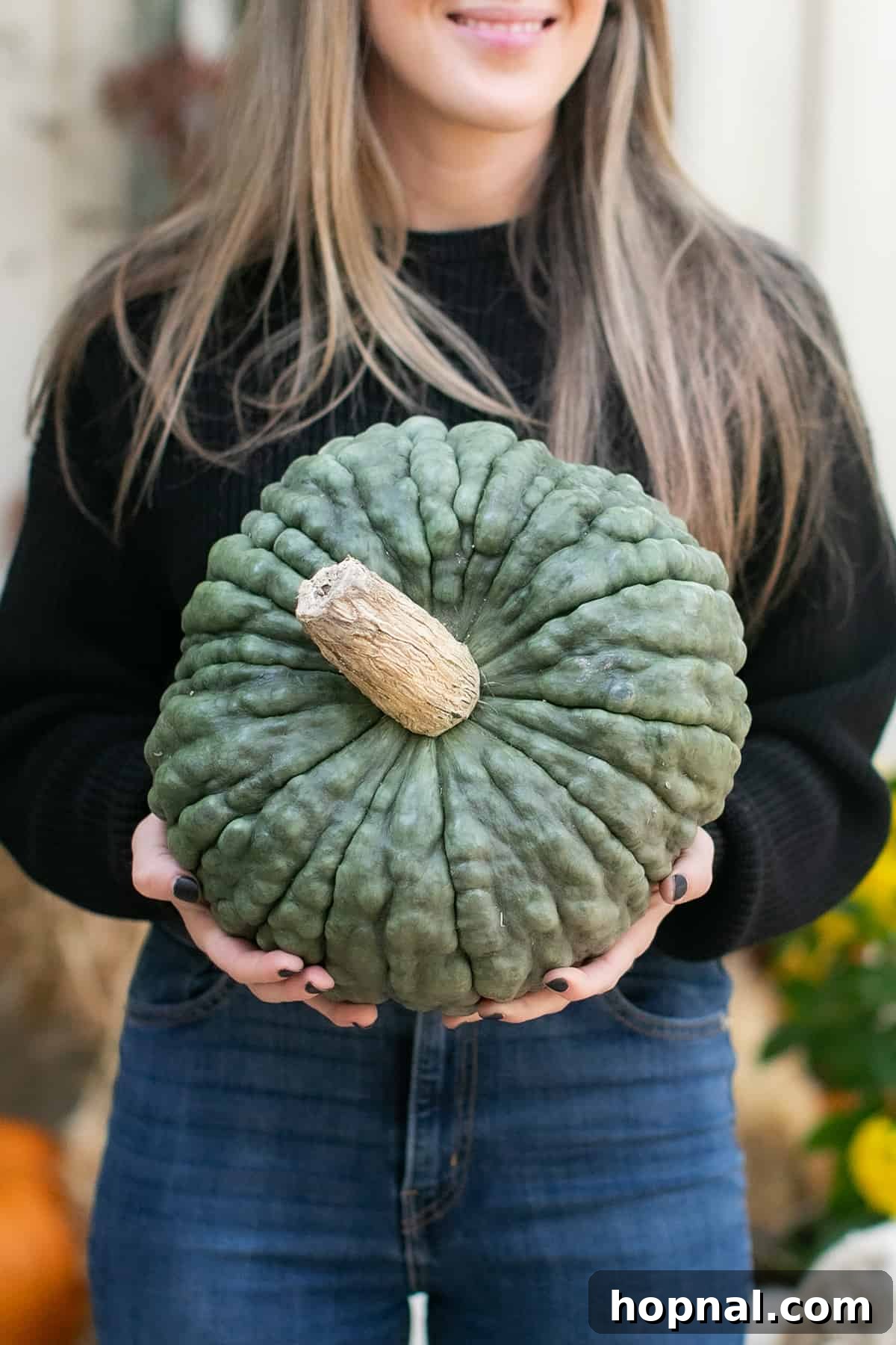 Eden Passante holding a green pumpkin. Eden Passante, an entertaining expert, proudly displays a unique green pumpkin on her beautifully decorated fall front porch.