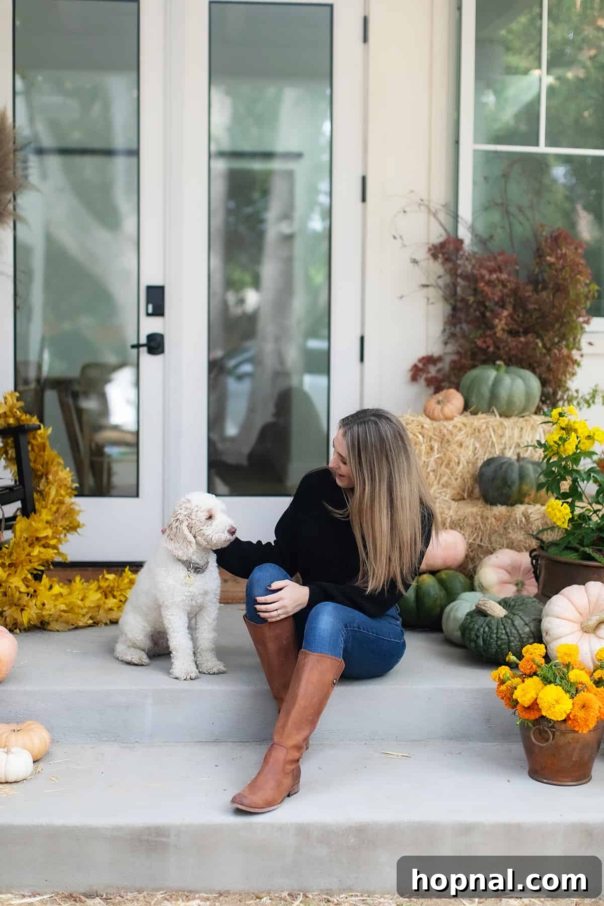 Eden Passante on her front porch with her dog. Entertaining expert Eden Passante enjoying her beautifully decorated fall front porch alongside her beloved dog, showcasing a perfect blend of cozy autumn decor and pet-friendly living.