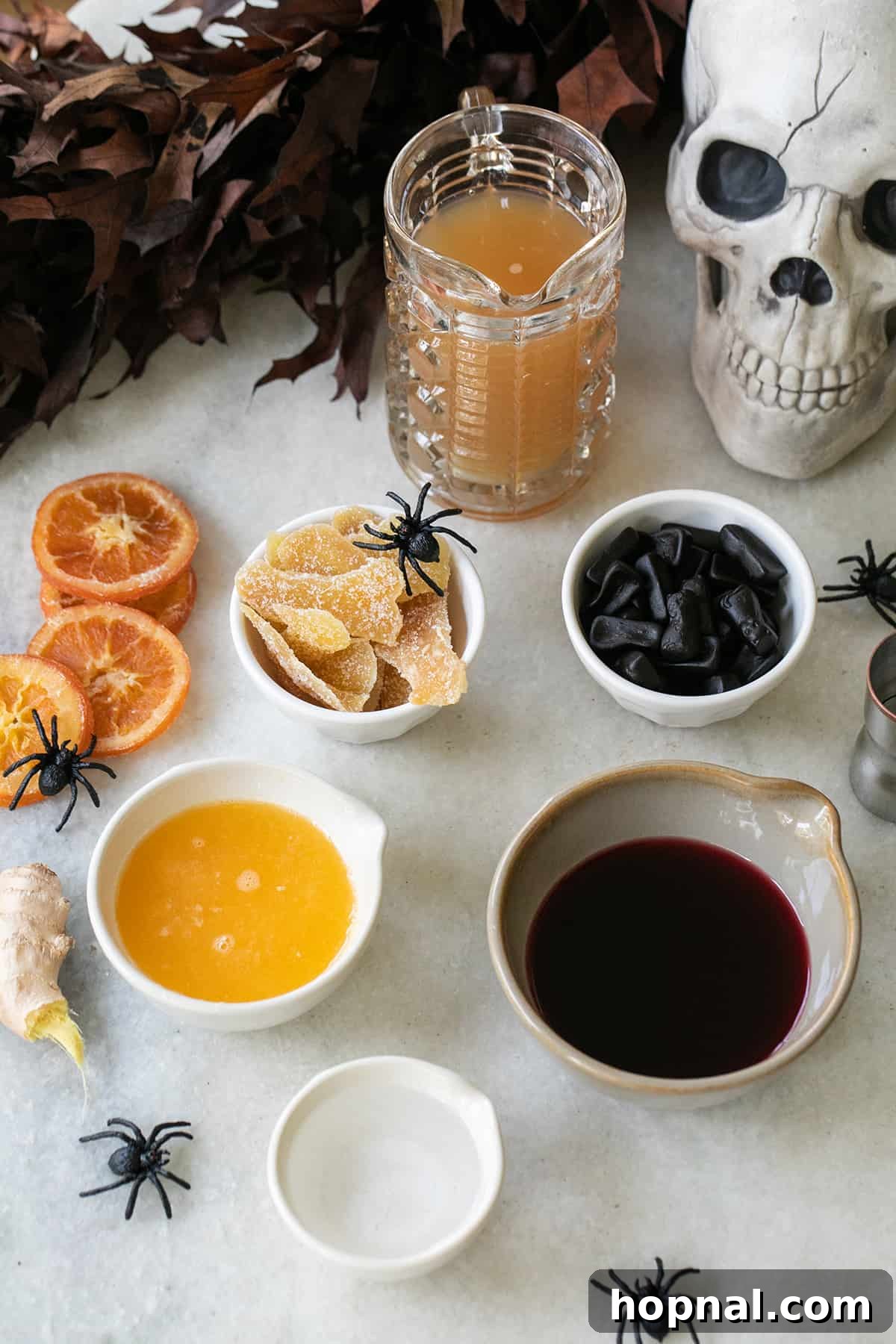 Fresh ingredients laid out on a table for making the Witches Brew cocktail, including apples, oranges, and pomegranates.