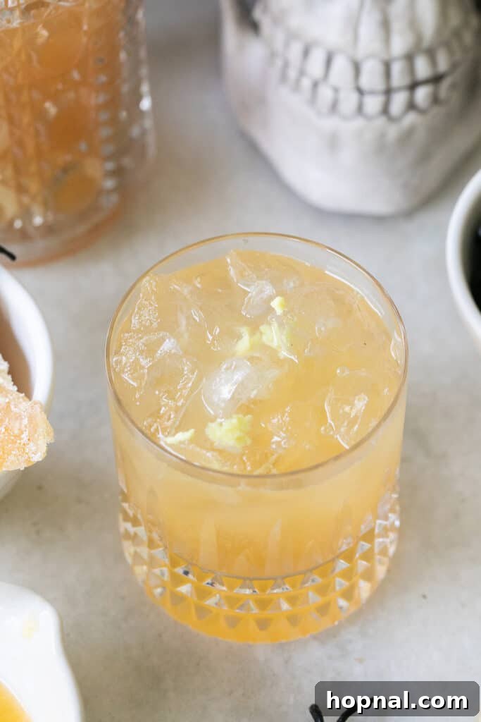 Grated fresh ginger being added to a cocktail glass, part of the Witches Brew preparation.