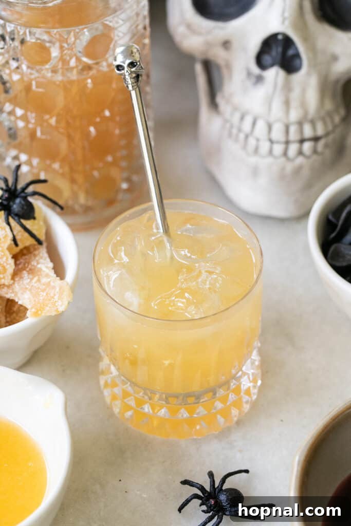 A person stirring a Witches Brew cocktail in a glass, mixing the ingredients for a seamless flavor blend.