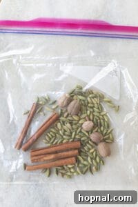 Mulling spices, including cinnamon sticks, being gently crushed in a plastic bag.