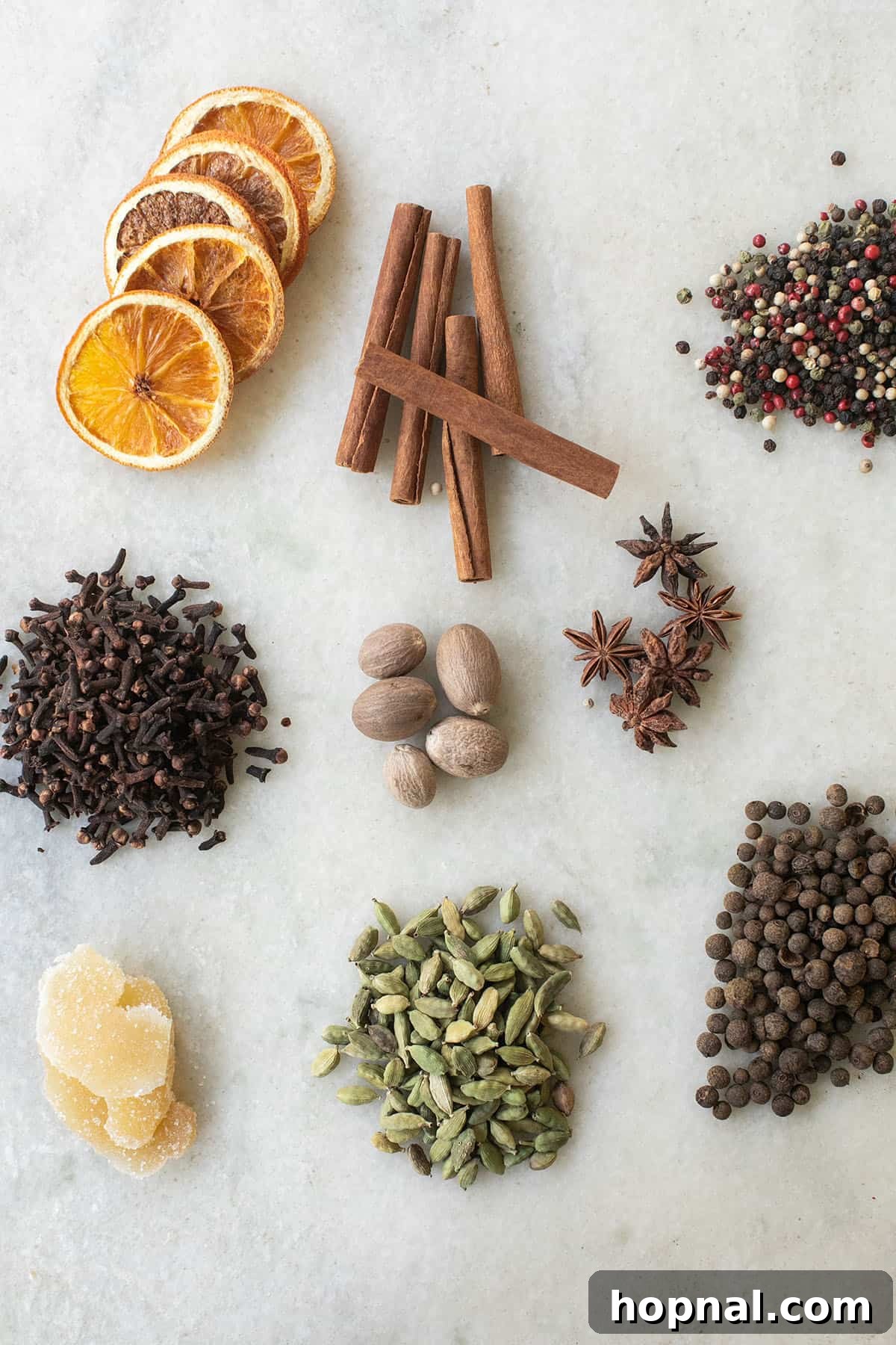 Ingredients for homemade mulling spices including whole spices, dried orange, and candied ginger.