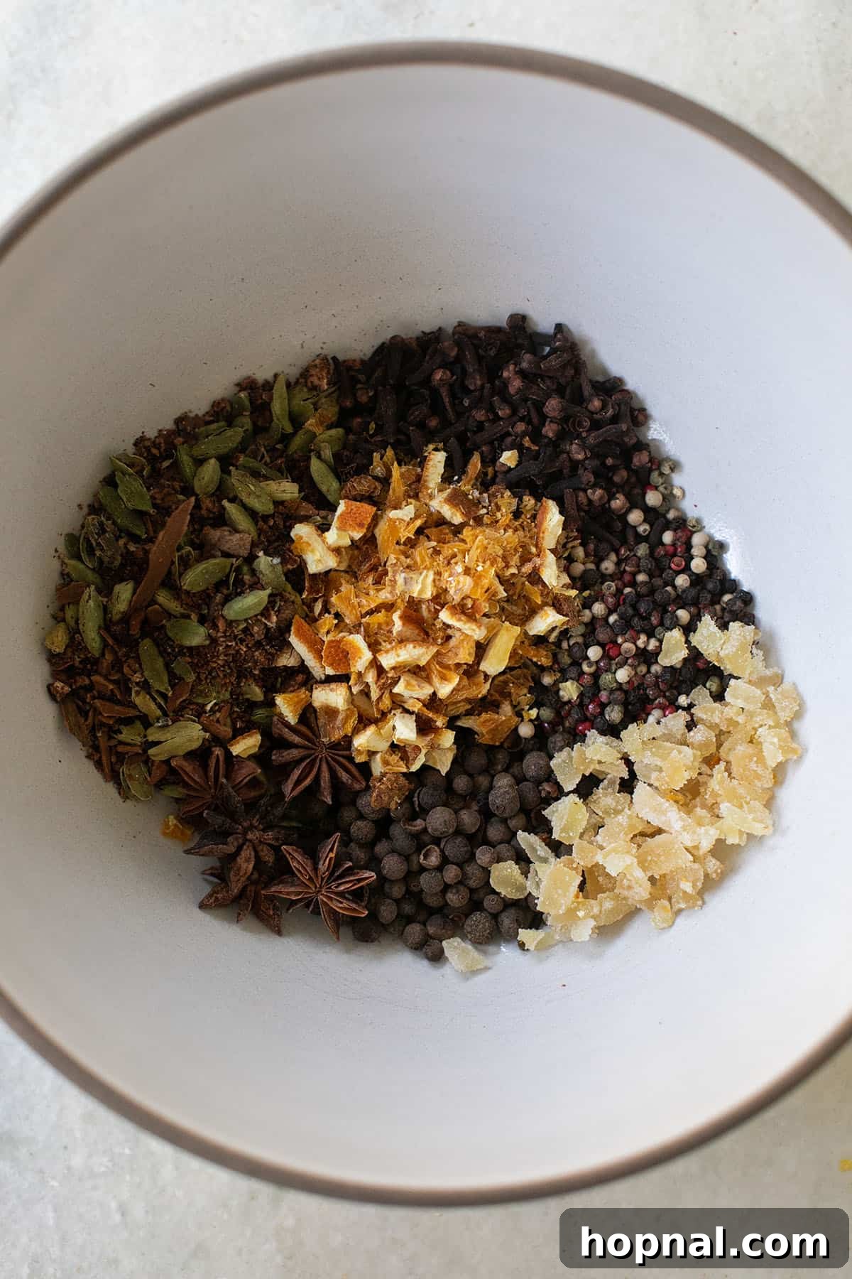 Close-up of mulled cider spices with cinnamon sticks, dried orange peel, and various whole spices.