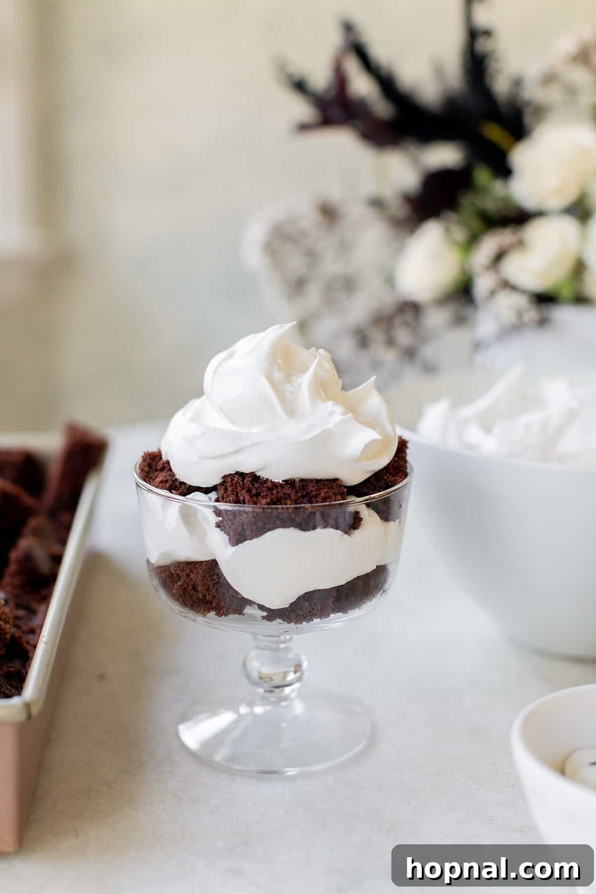 A mini trifle dish demonstrating beautifully layered chocolate cake alternating with fluffy white whipped cream, showcasing the simple assembly process
