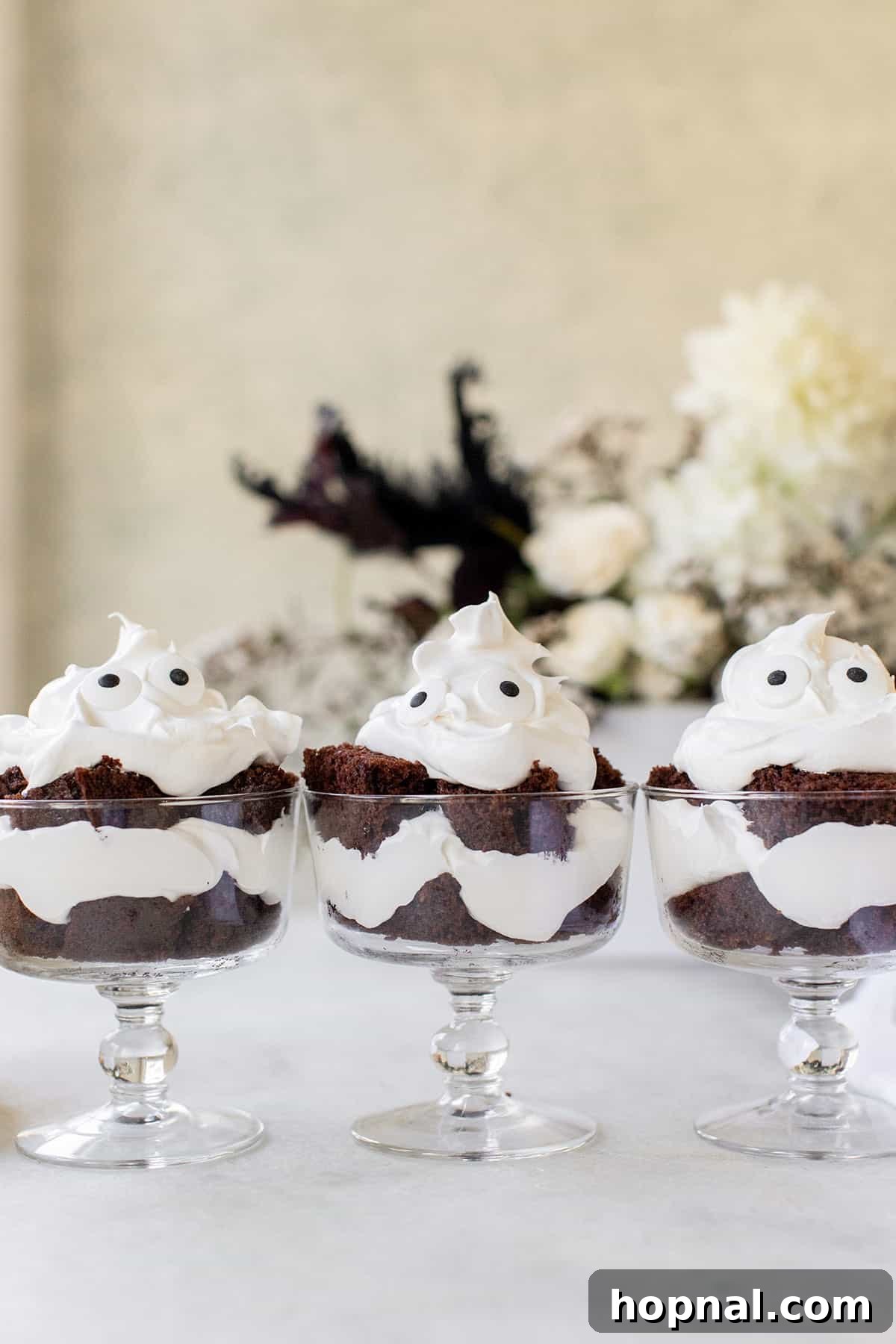 A beautiful cluster of individual mini ghost chocolate trifles, artfully presented on a clean white serving tray, highlighting their delightful design and layered texture for a festive Halloween celebration