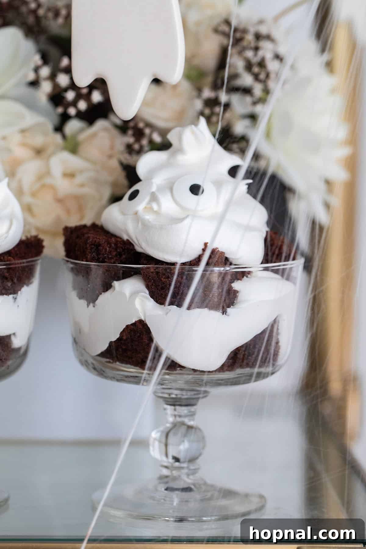 Three perfectly crafted mini ghost chocolate trifles, each with fluffy whipped cream and expressive candy eyes, displayed on a minimalist background, highlighting their festive appeal as easy Halloween desserts