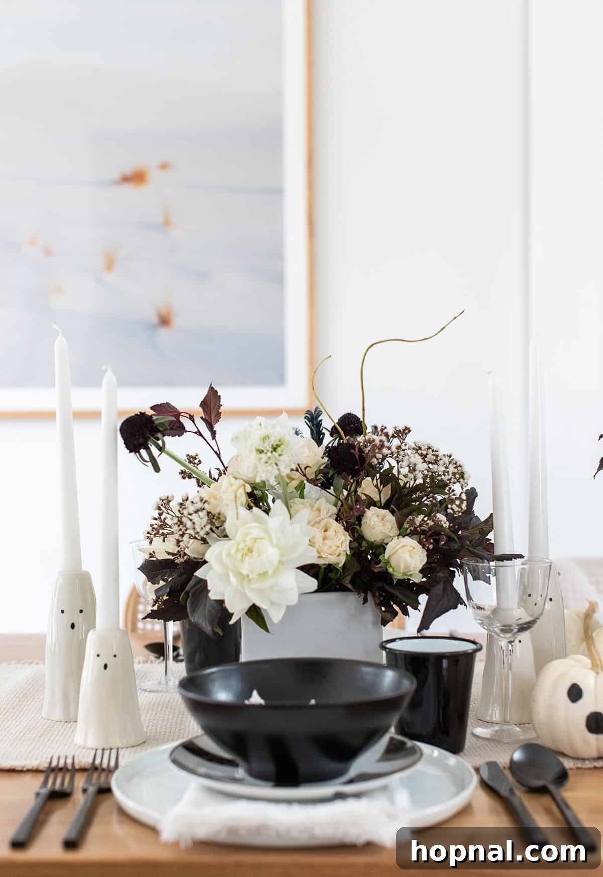 An elegantly set Halloween table with ghost-themed decorations.