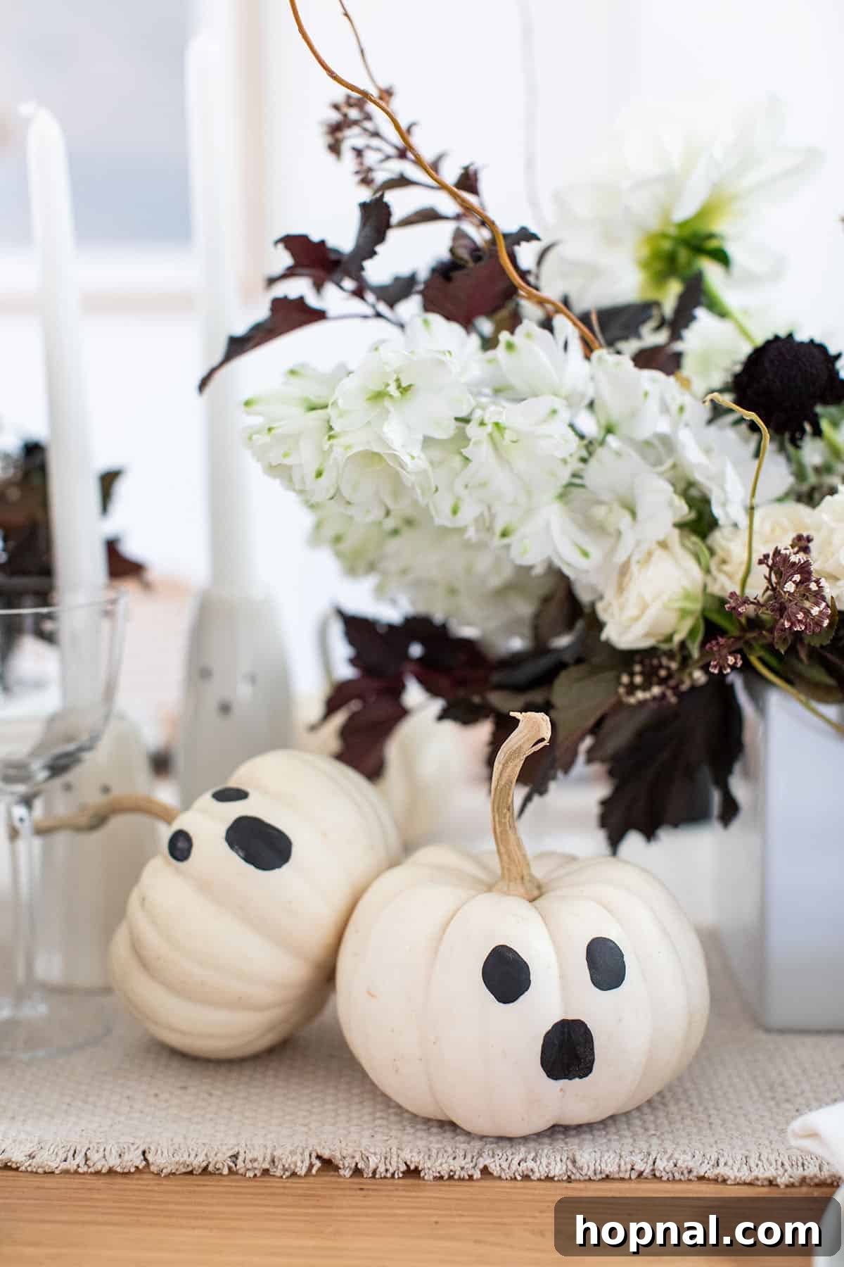 Mini white pumpkins painted with simple ghost faces.