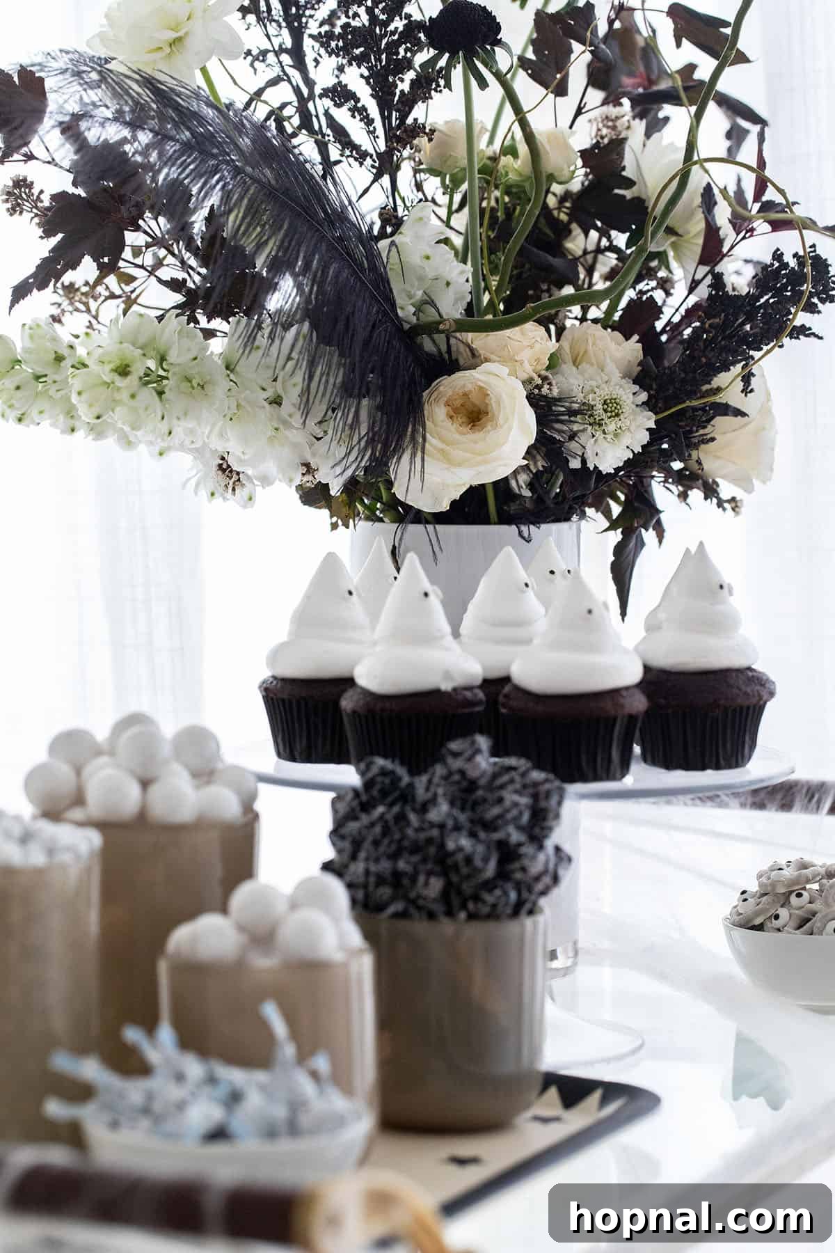 Halloween candy and ghost cupcakes artfully arranged on a treat bar.