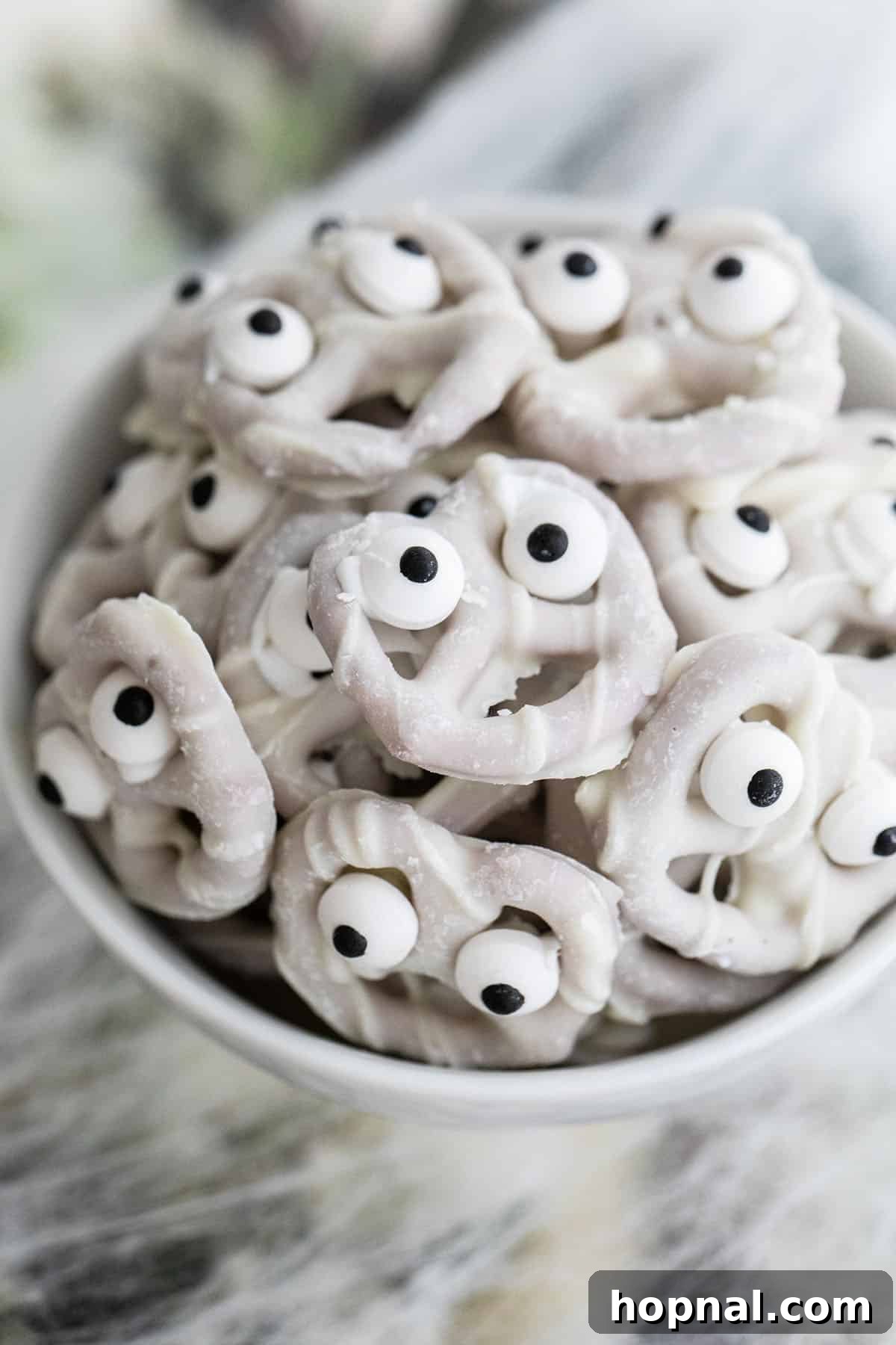 Mini yogurt pretzels adorned with edible ghost eyes.