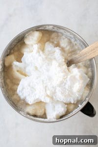 Folding whipped egg whites into the eggnog mixture.