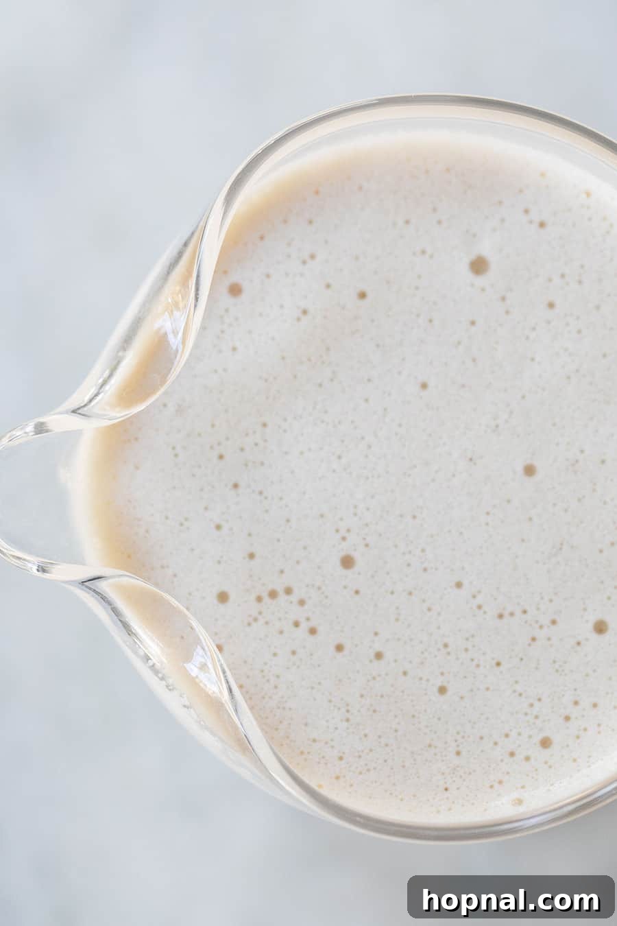 Homemade spiked eggnog elegantly displayed in a clear glass pitcher, ready for serving at a festive holiday gathering.